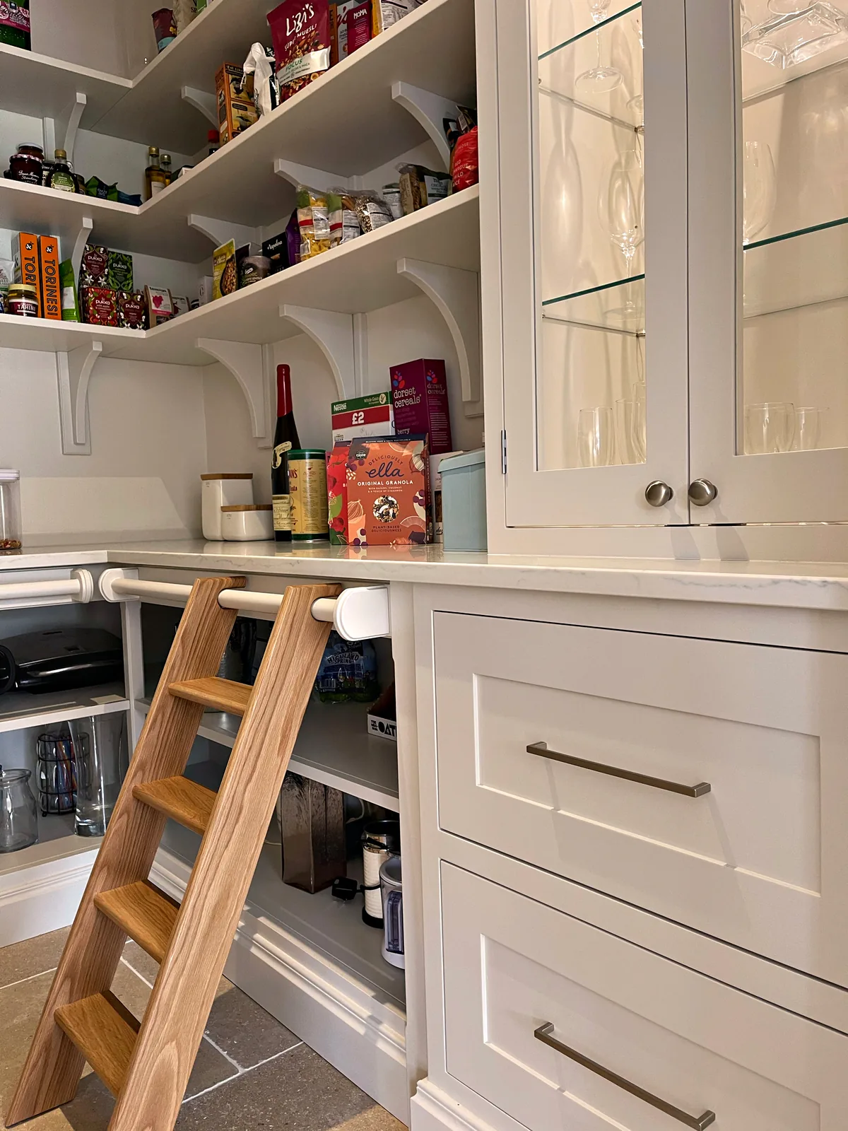 Walk in pantry with open shelving, a glazed cabinet and an oak library ladder