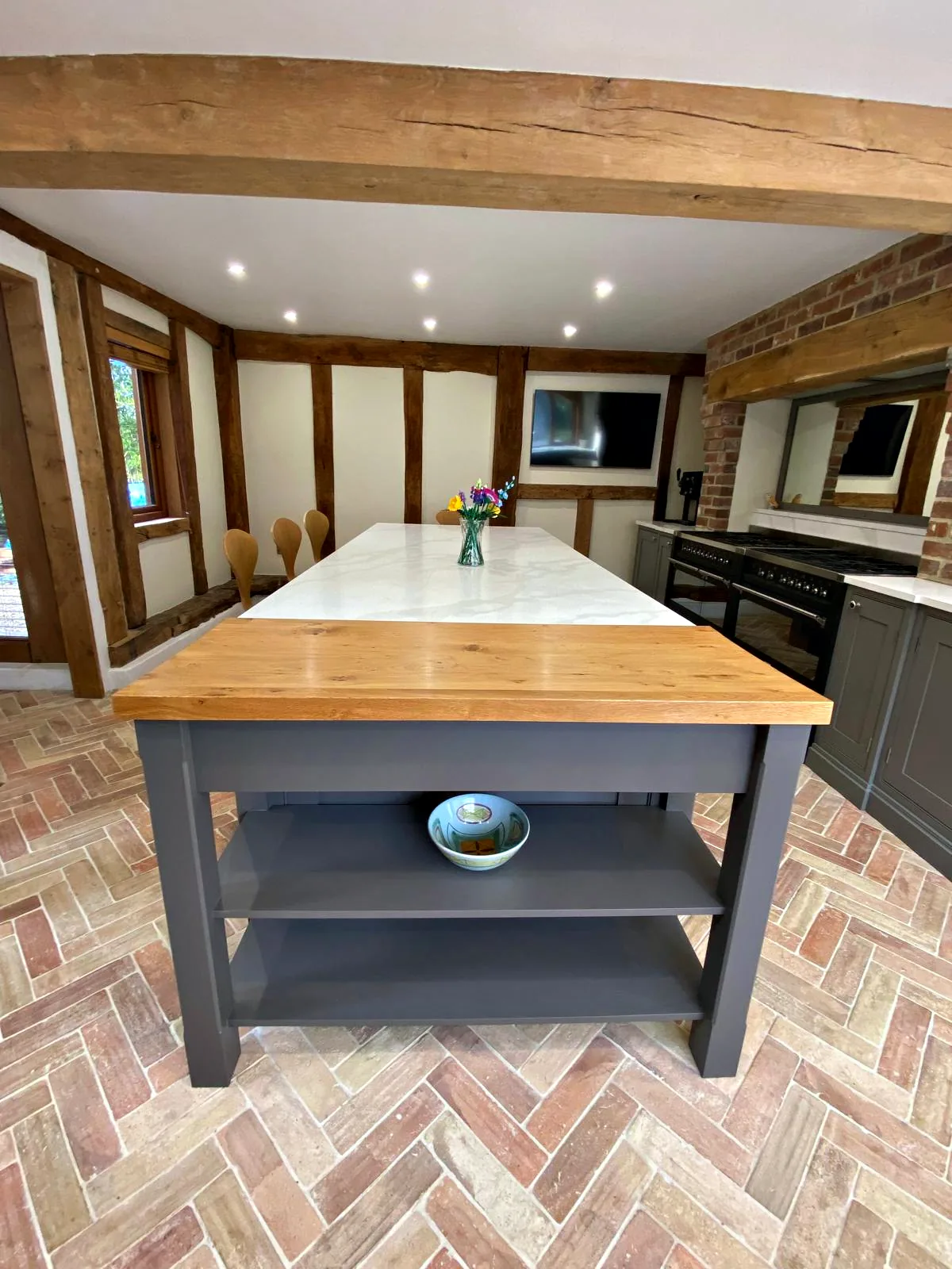 Dark taupe island with an oak topped end and open shelves below in the oak framed Barn Owls kitchen