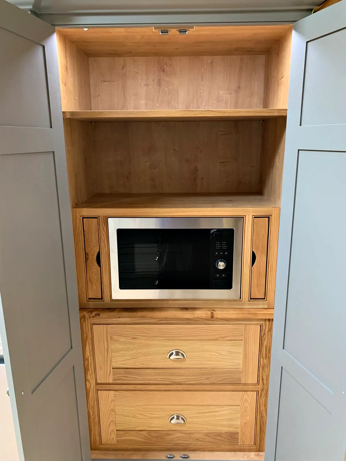 Larder niche with a built in microwave above oak drawers with nickel cup handles