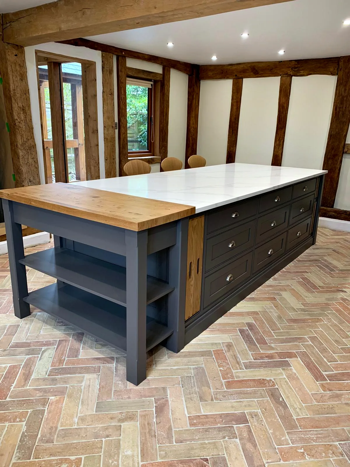 Island with an oak topped breakfast table end and dark taupe drawers in an oak framed kitchen