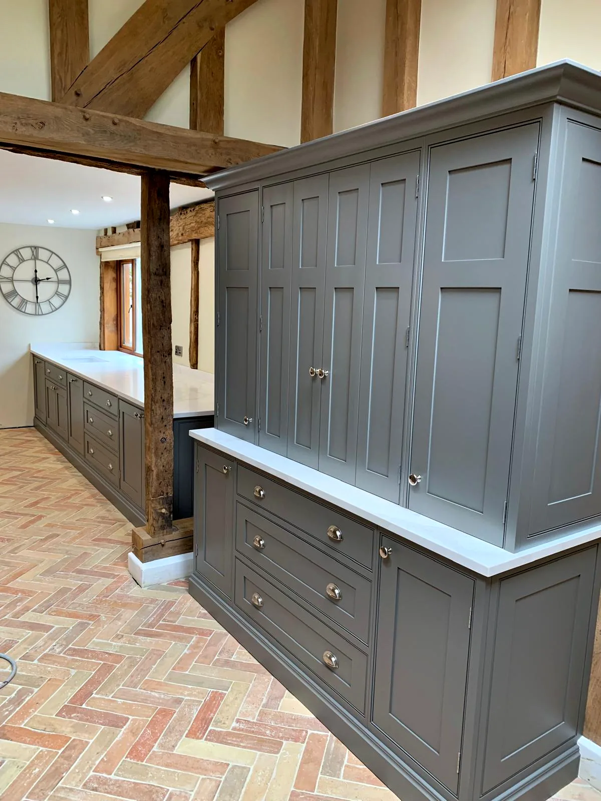 Tall dark taupe dresser with panelled doors and drawers beneath the oak frame