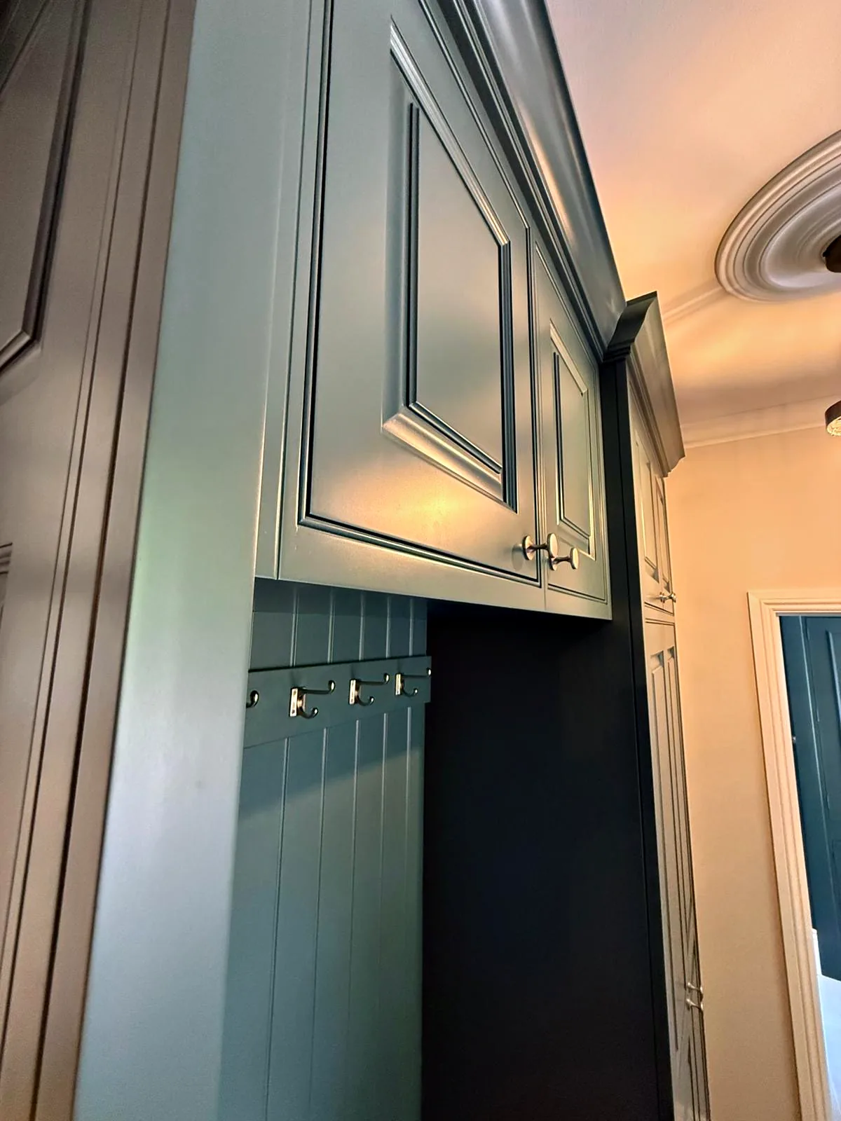 Deep teal boot room unit with raised and fielded doors, tongue and groove panelling and coat hooks