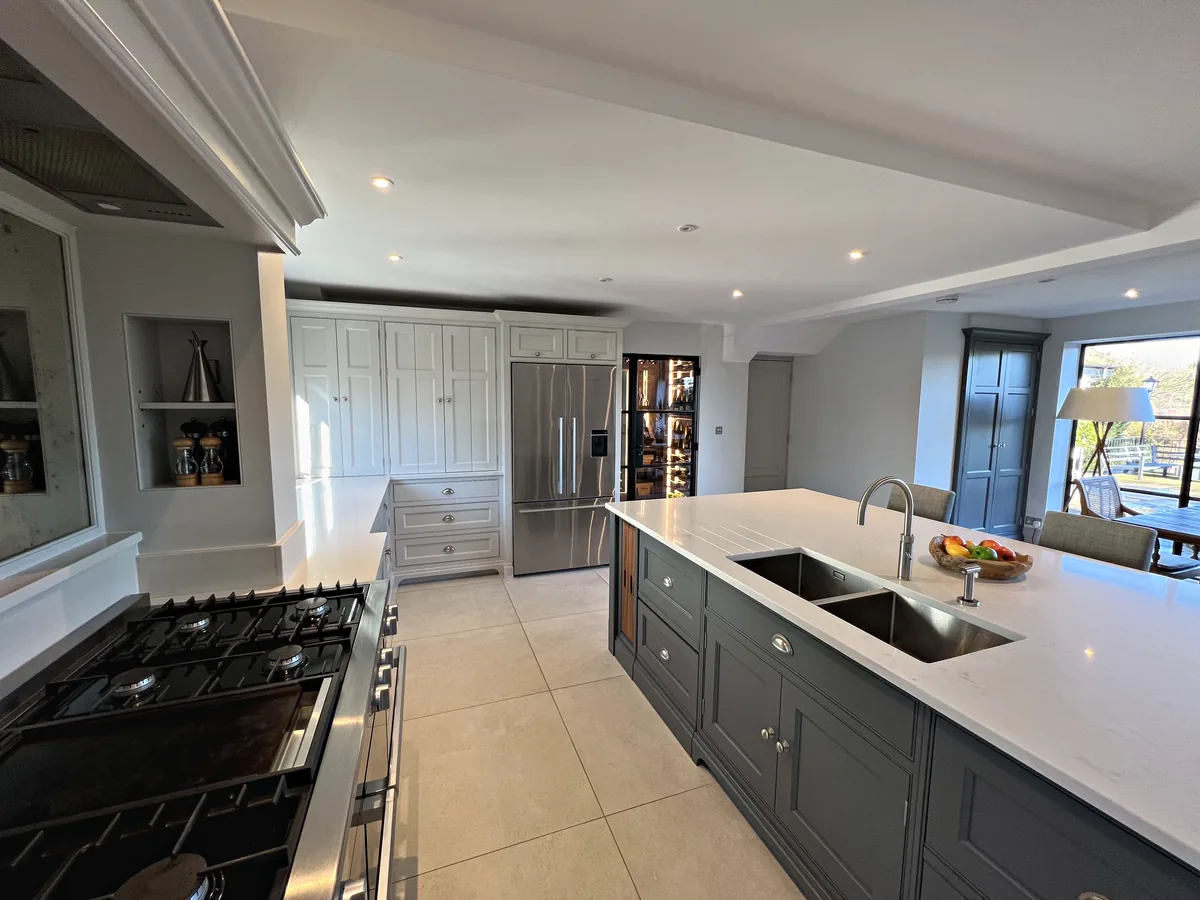 Range hob in the foreground with the island's twin sinks and tall pale grey units beyond