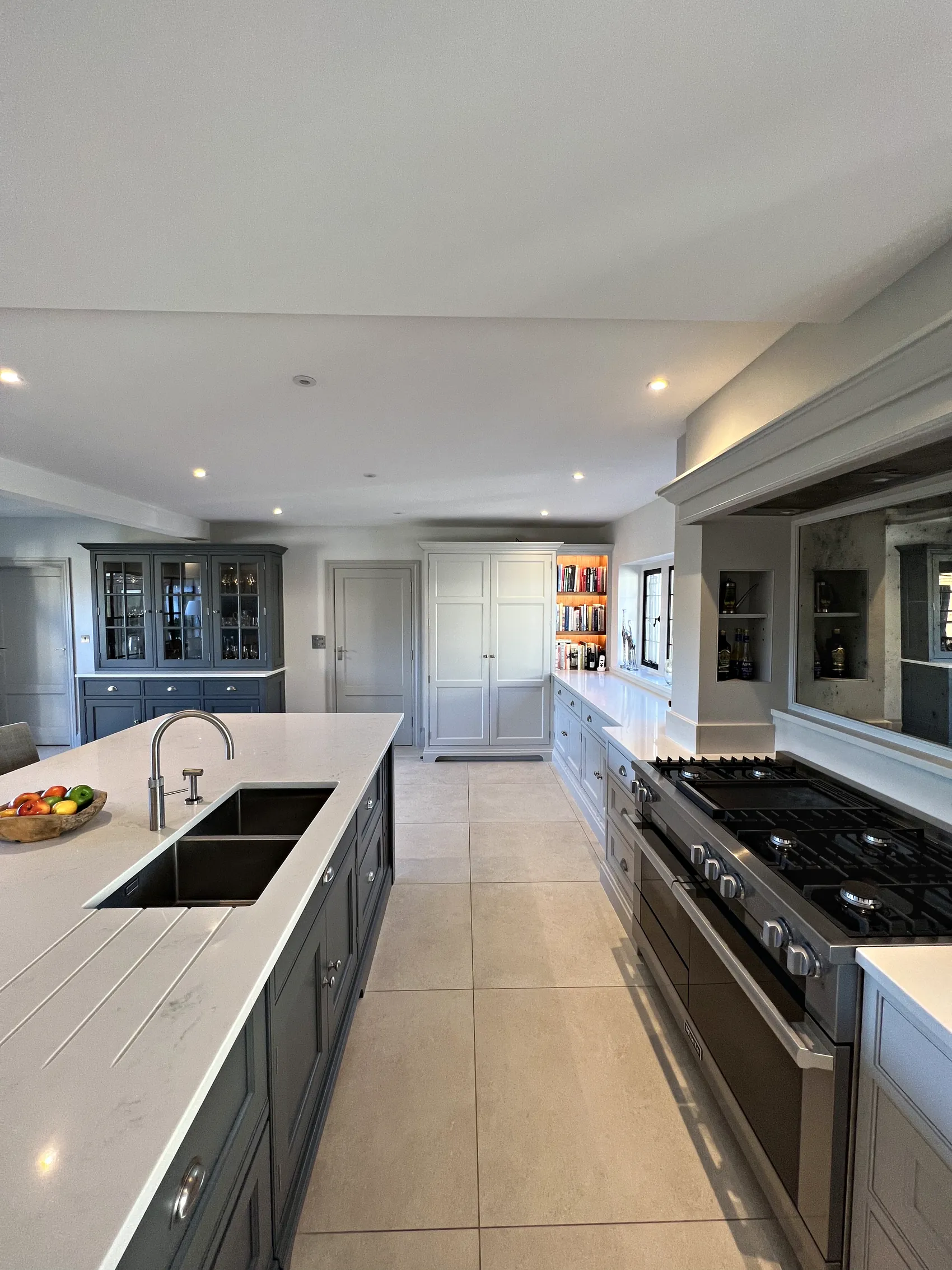 Island sink and range run leading to the glazed dresser and a tall larder