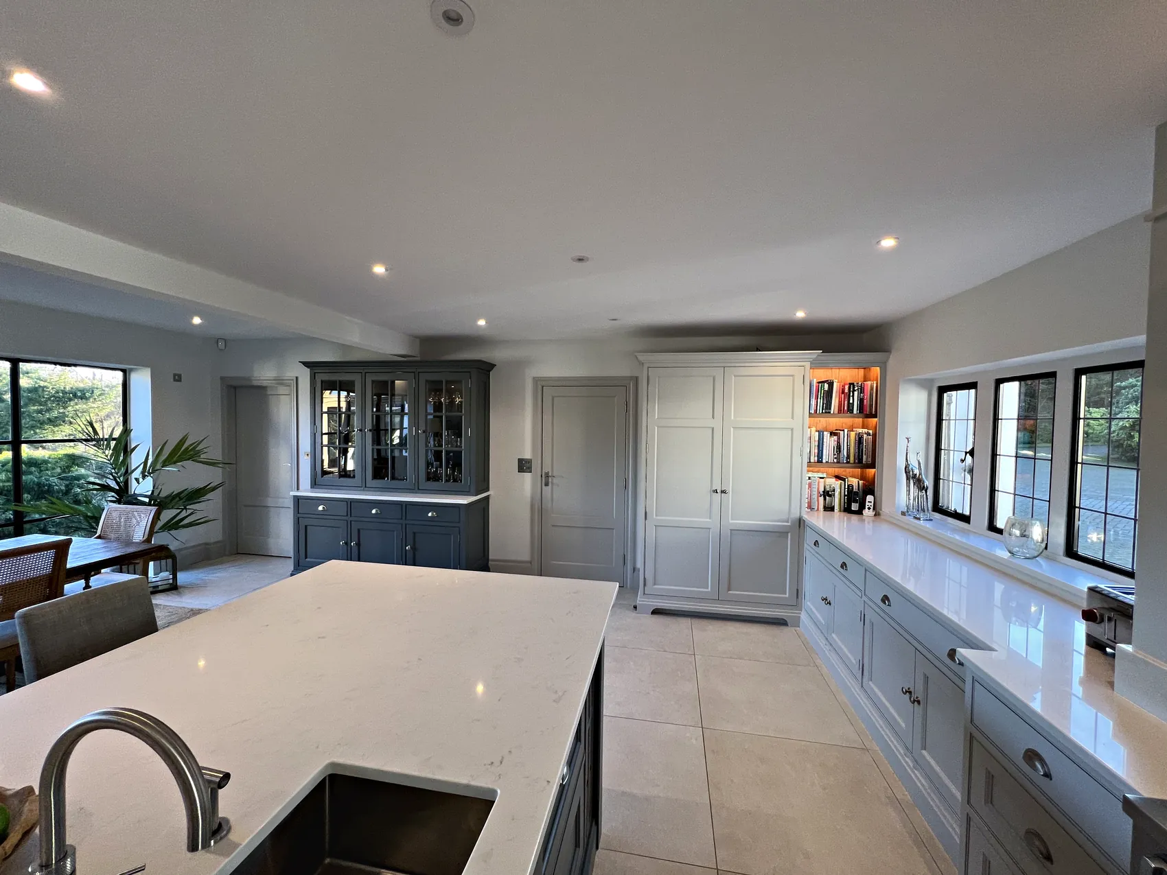 Glazed dresser, a tall larder cupboard and the wall run under the windows seen from the island