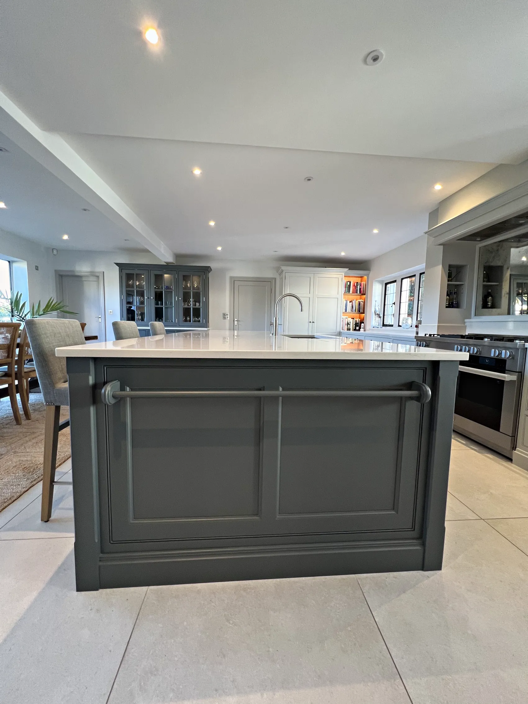 End of a slate grey island with panelled doors and a towel rail in an open plan kitchen