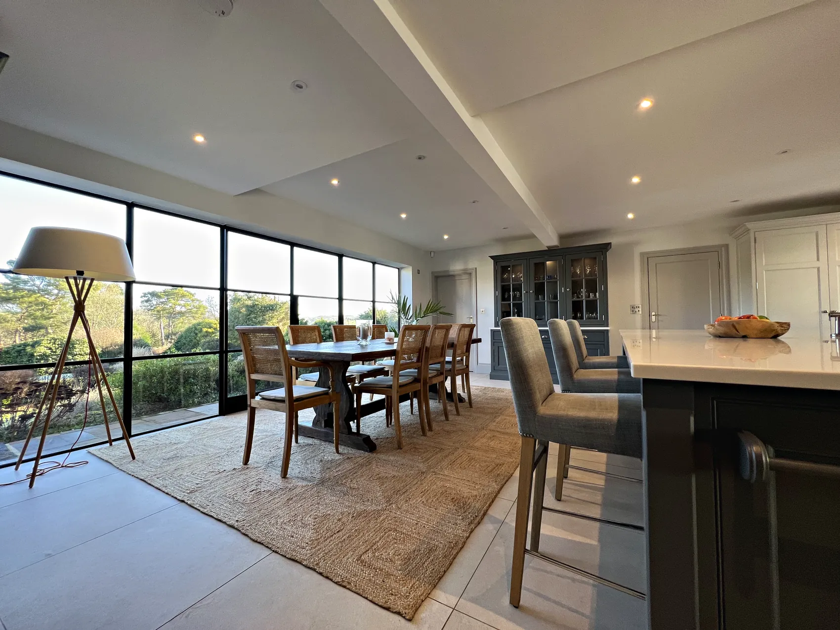 Dining area beside black steel glazing with the island stools and the glazed dresser beyond