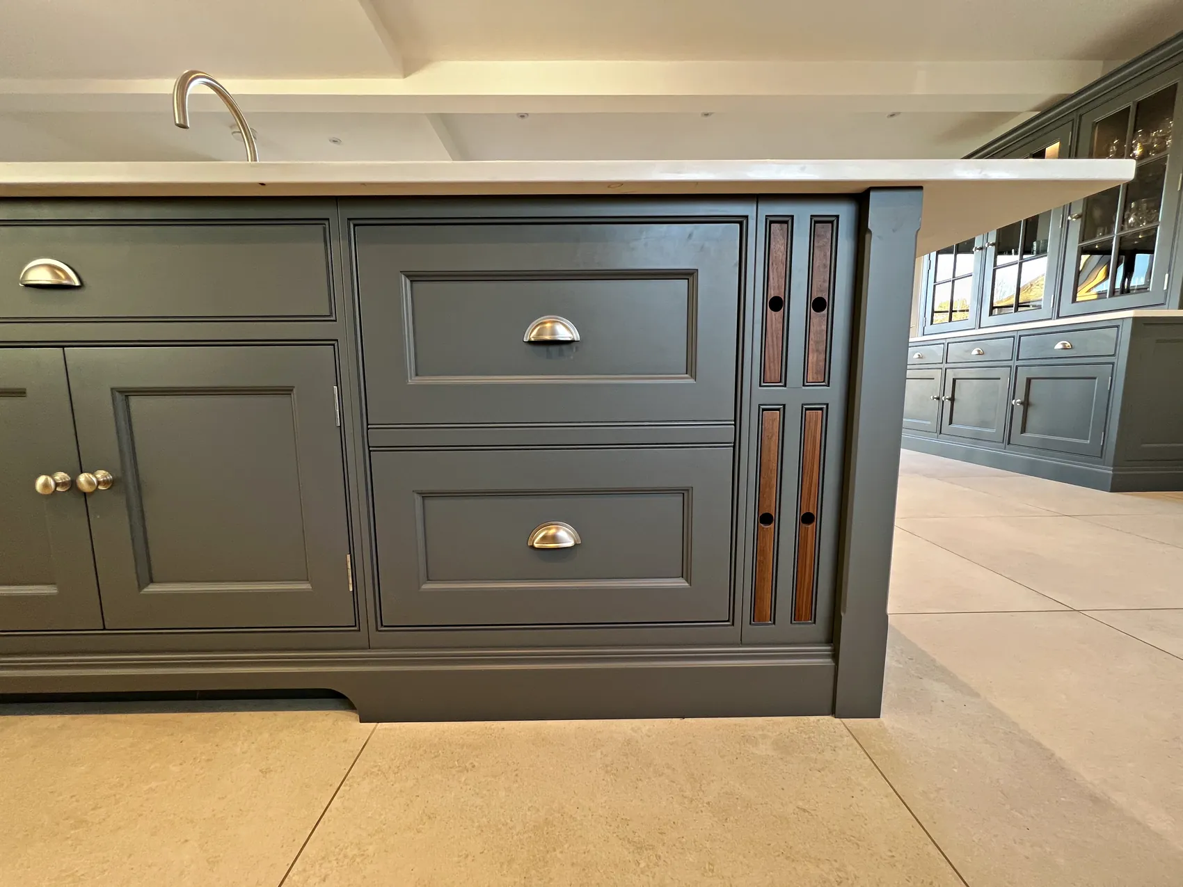 Island base with nickel cup handles on inset drawers and walnut inset panels