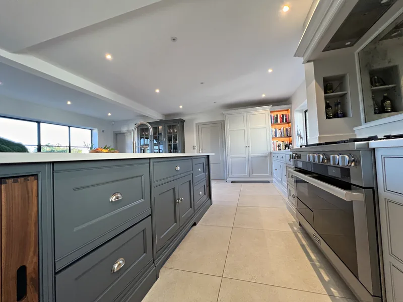 Island drawers with nickel cup handles running towards the dresser, a tall larder and the range