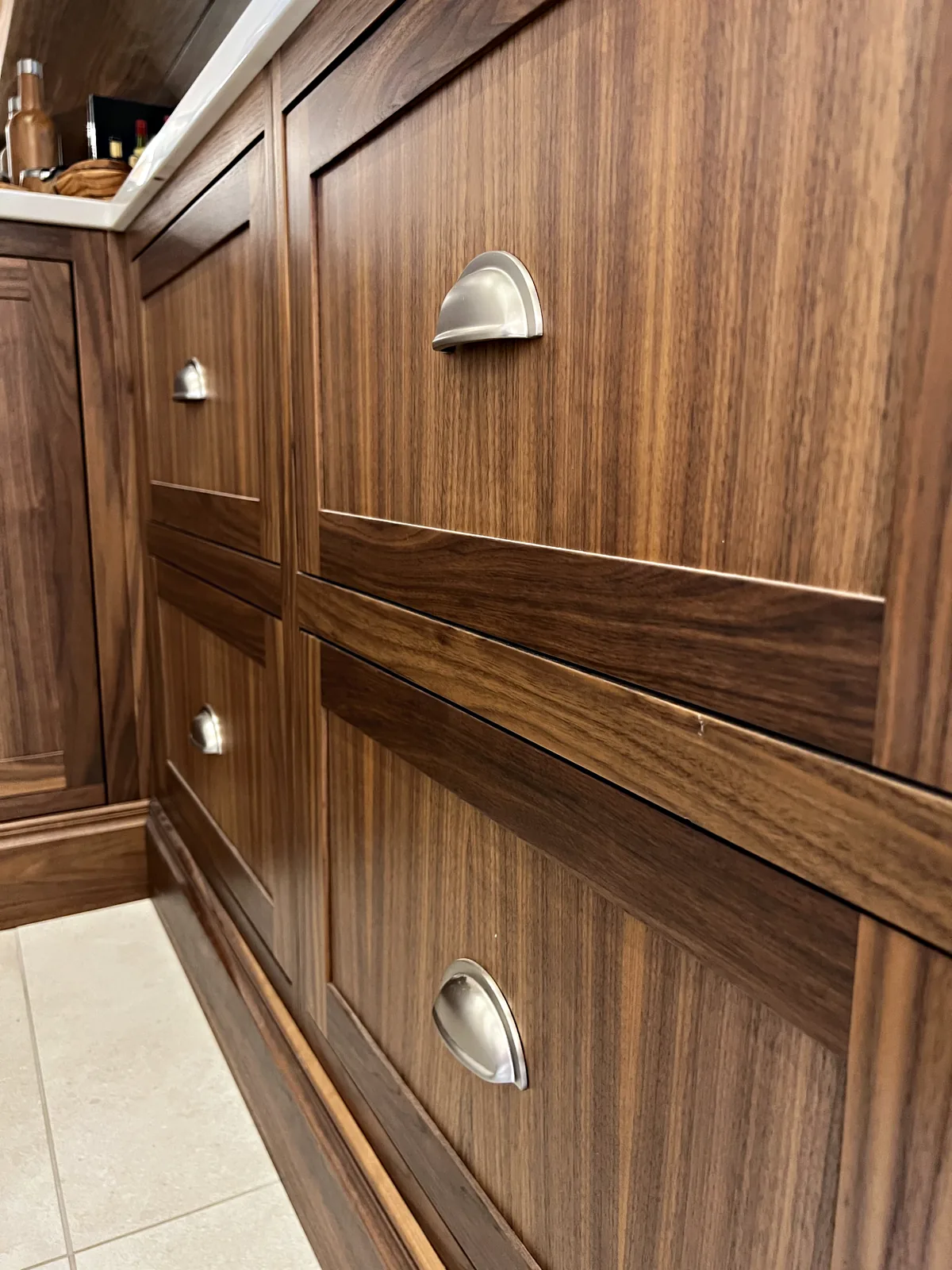 Walnut drawer fronts with nickel cup handles in the wine room