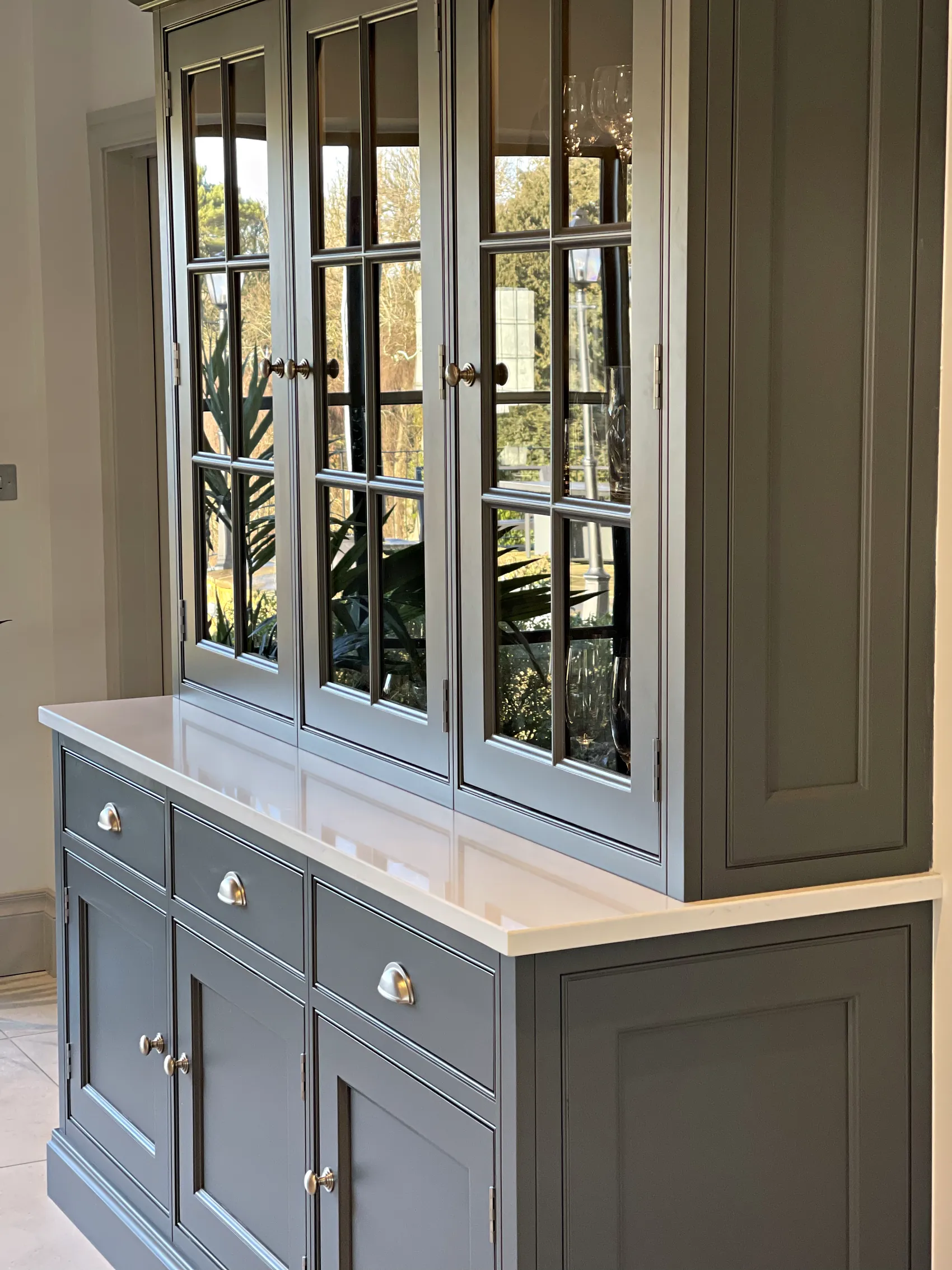 Slate grey glazed dresser with in frame doors and cup handled drawers under a white worktop