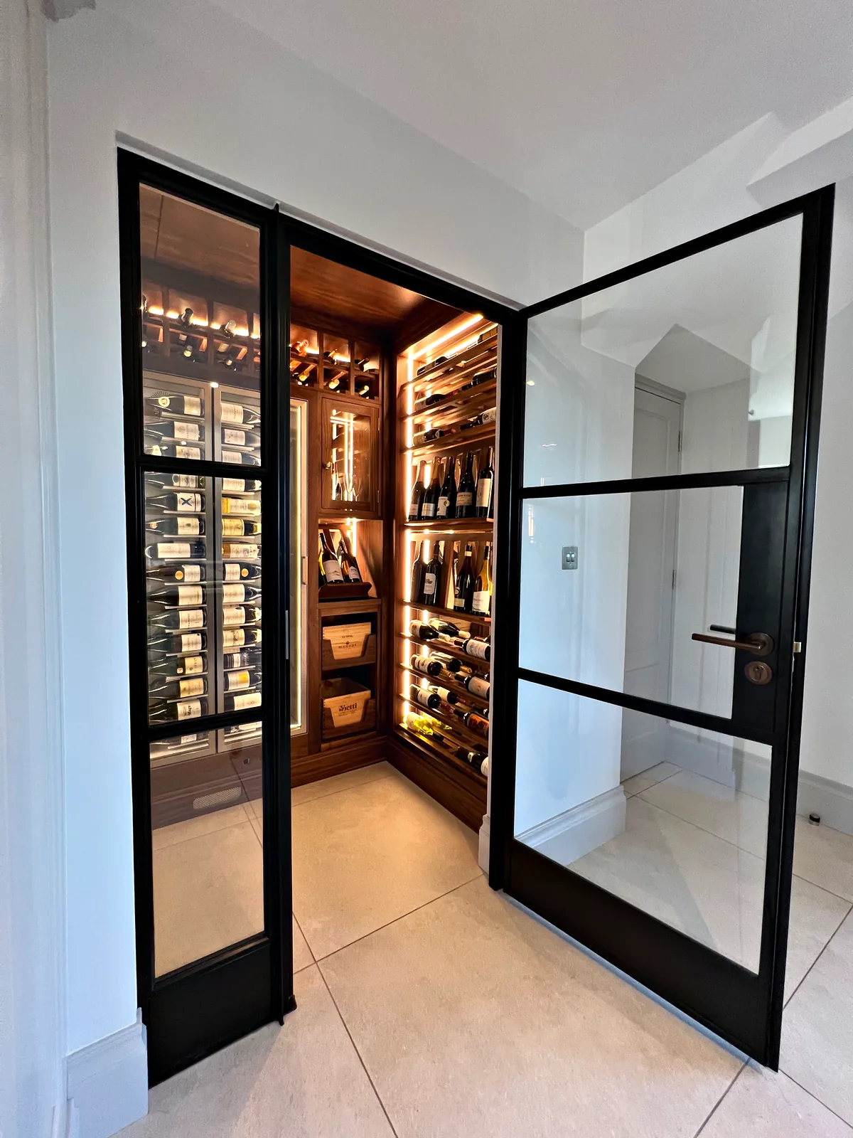 Black steel glazed doors opening into the walnut wine room