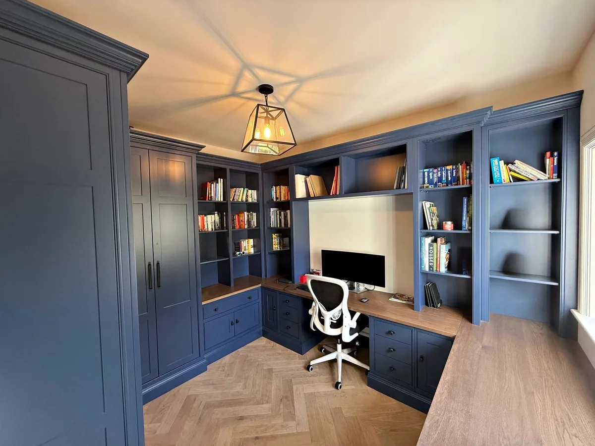 Navy study at The Hollowes with bookshelves, tall cupboards and an L shaped desk with an oak top