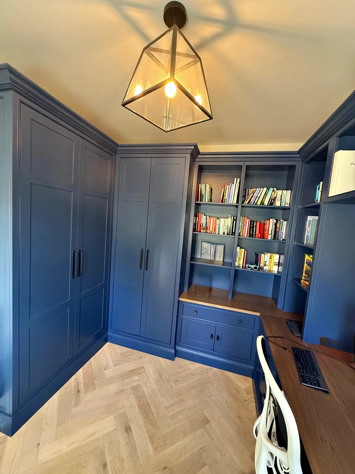 Navy study with full height cupboards, open bookshelves and a desk with an oak top
