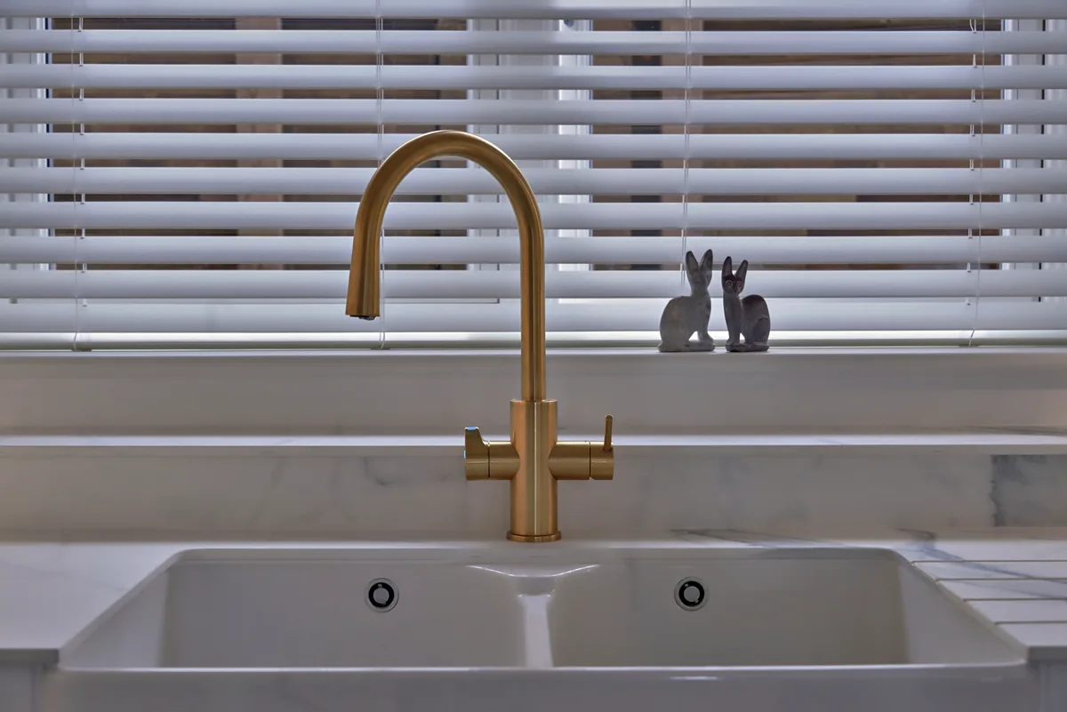 Brushed brass tap over a twin undermount sink in a marbled quartz top