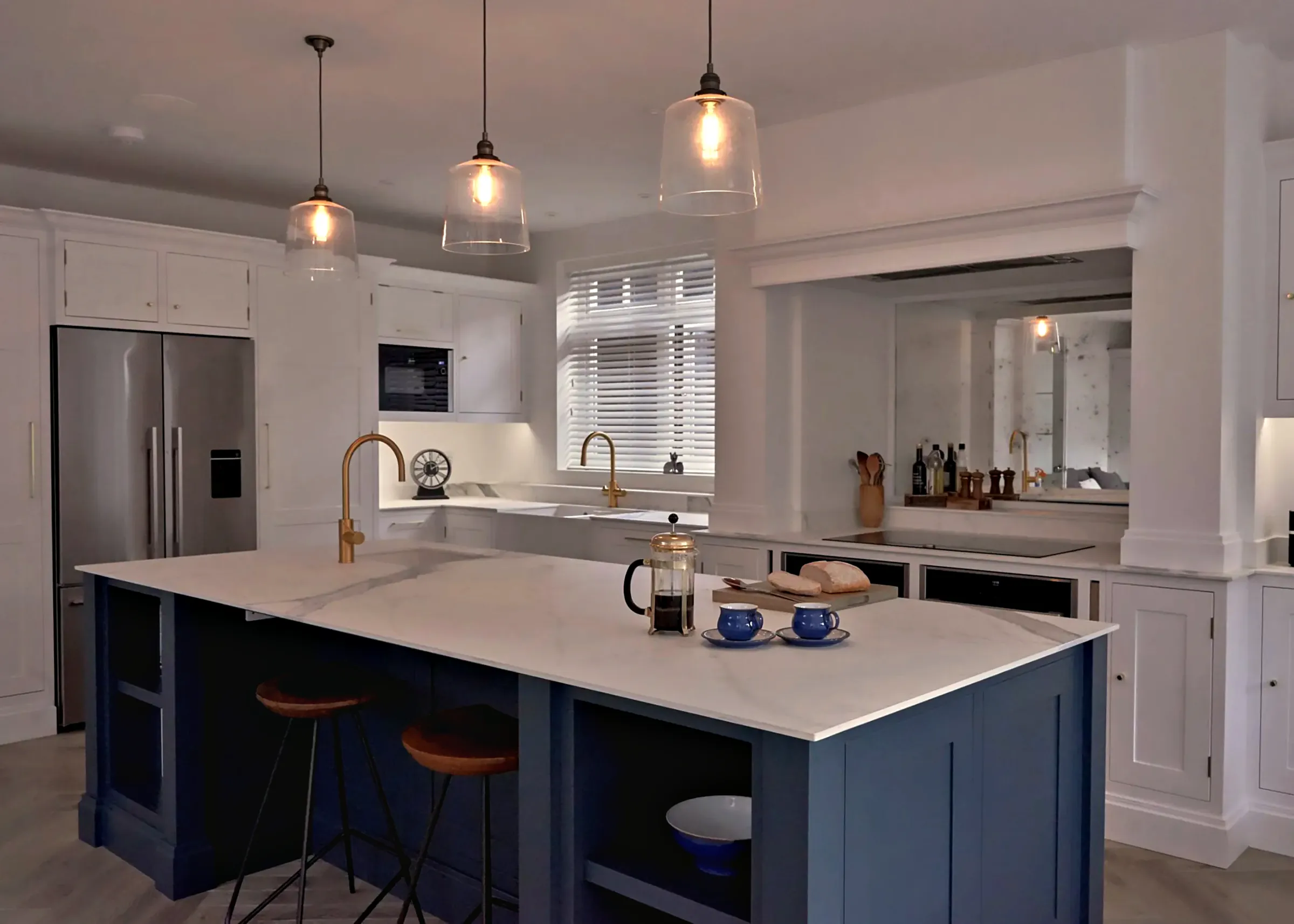Malbrook kitchen in All White with a Hague Blue island, brass taps and a mirrored splashback under the mantel