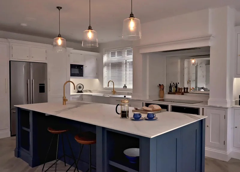 Malbrook kitchen in All White with a Hague Blue island, brass taps and a mirrored splashback under the mantel