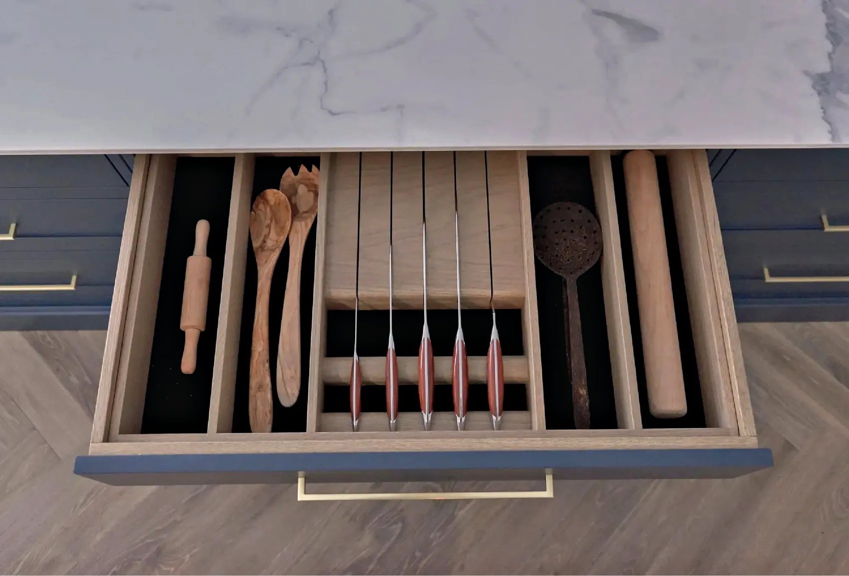 Cutlery drawer with an oak knife block and utensil dividers below a marbled quartz top
