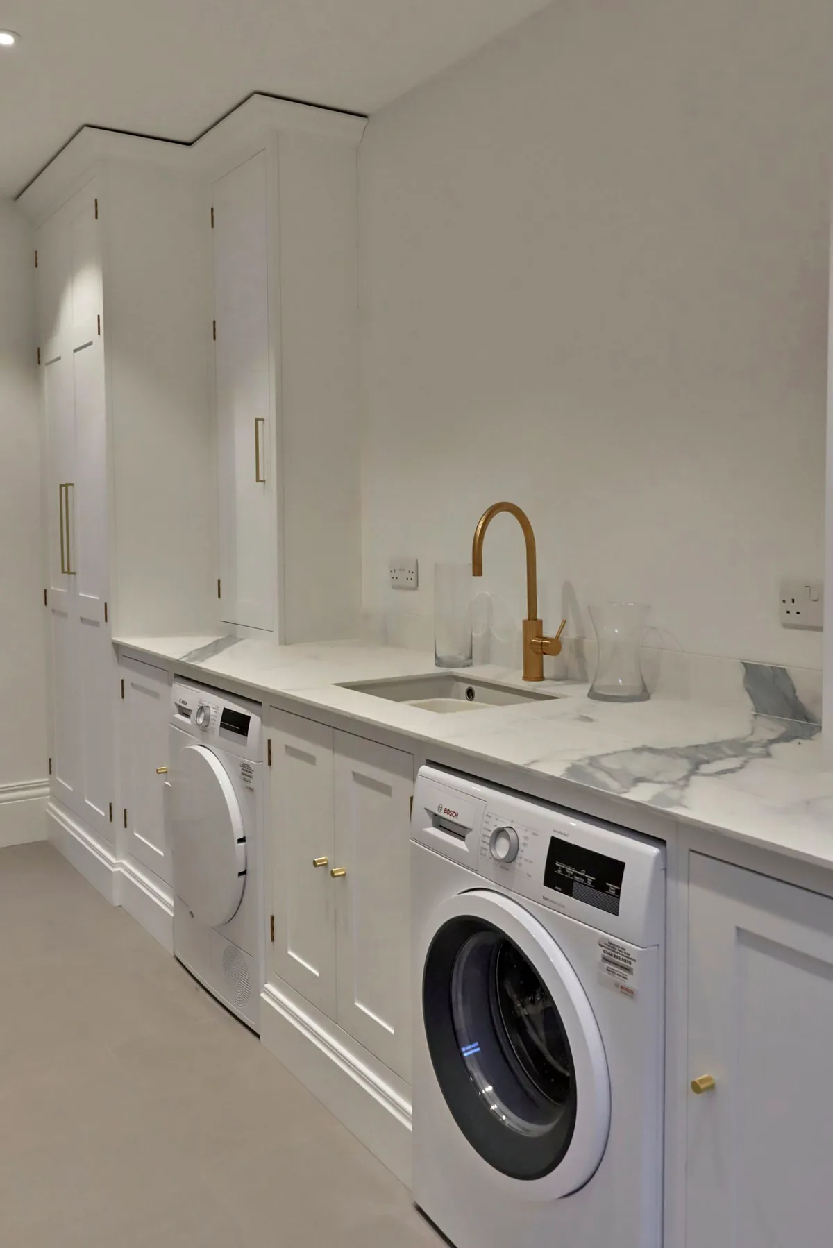 Utility room with a washing machine and a brass tap