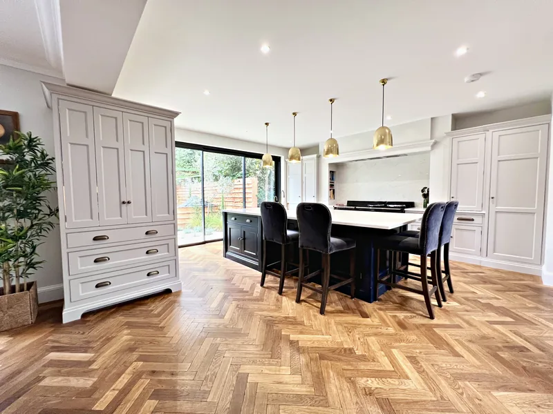 Freestanding larder cupboard and navy island in the Meadowcroft kitchen with a herringbone oak floor