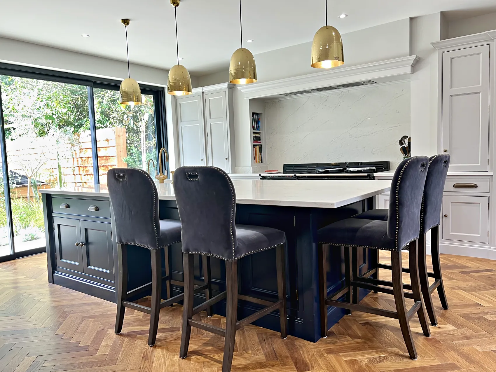 Bond Street island with navy velvet bar stools under brass pendants