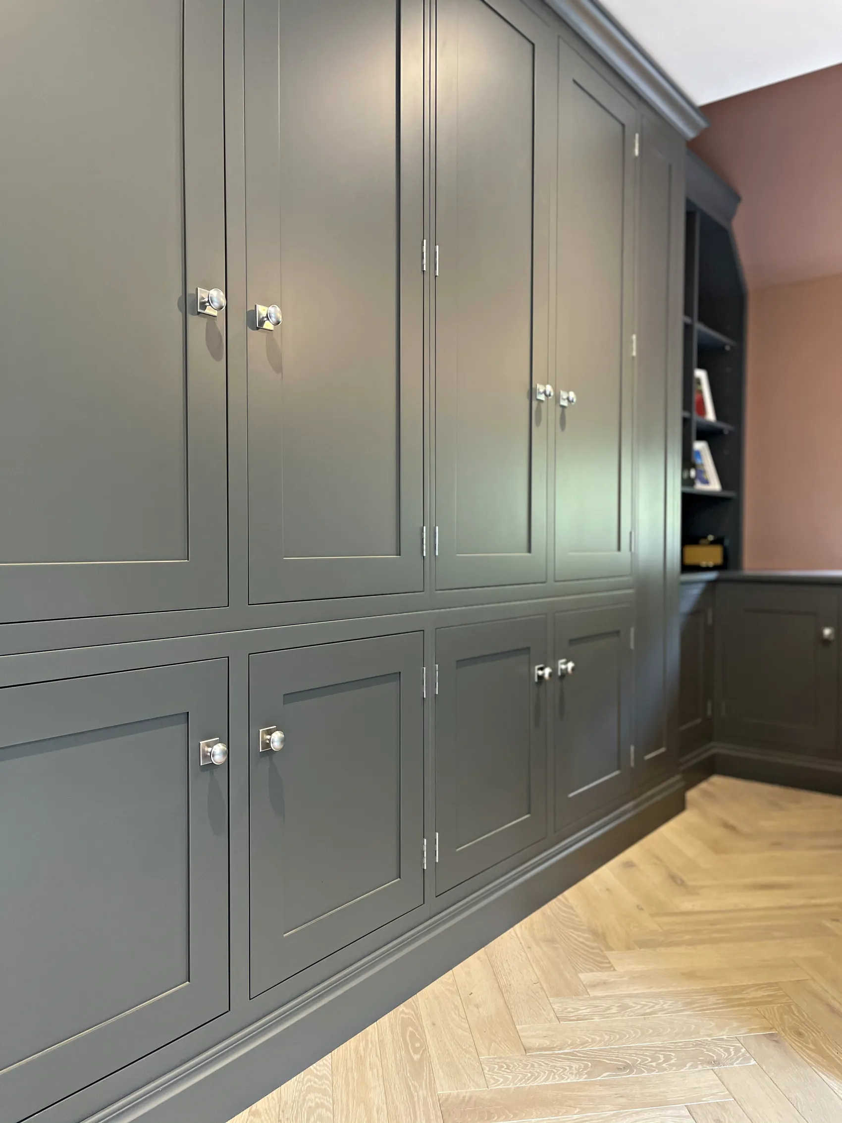Run of tall grey green study cupboards with open bookshelves at the end
