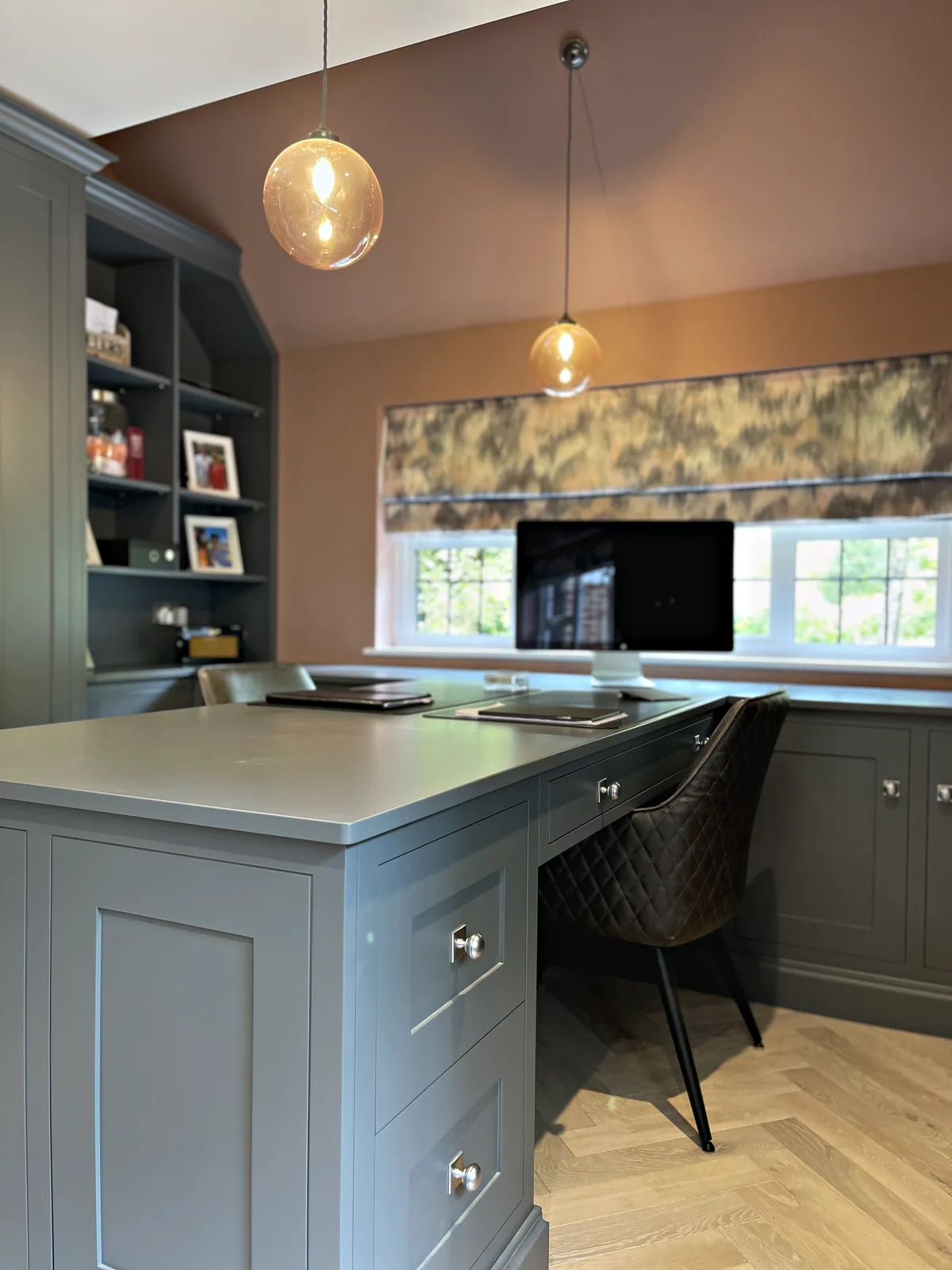 Grey green desk peninsula and desk run below the window under glass globe pendants