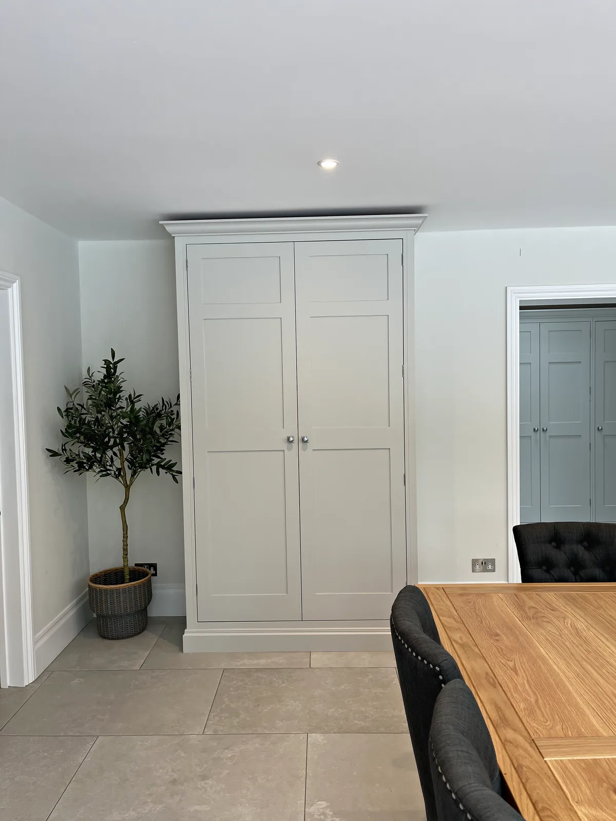 Freestanding pale grey larder cupboard with shaker doors and nickel knobs
