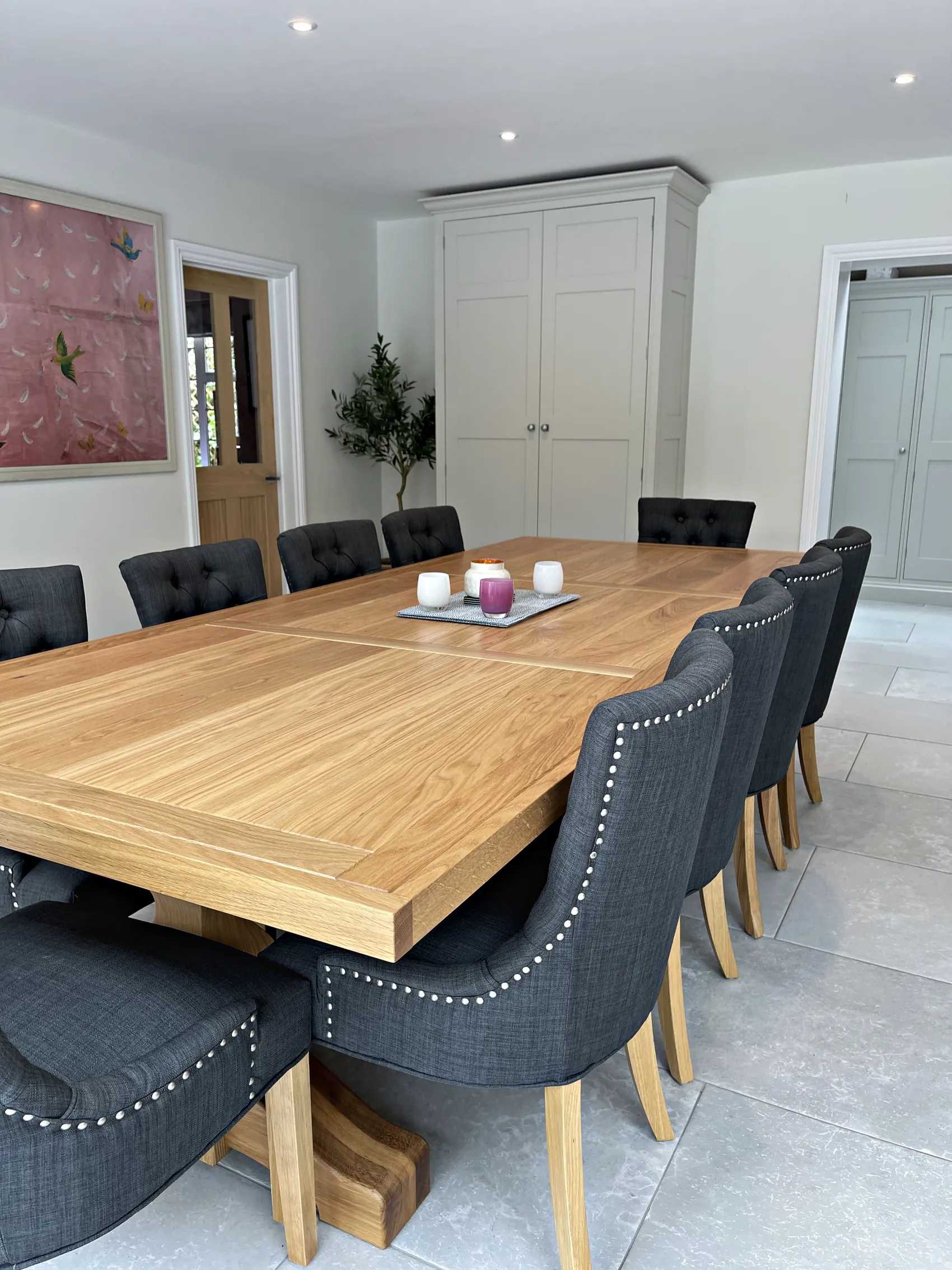 Oak dining table and buttoned chairs with the pale grey larder cupboard beyond