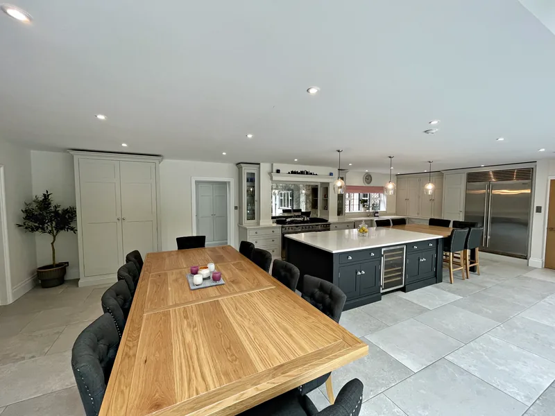 Munstead Plat kitchen and dining room with an oak table, the Off Black island and the range wall beyond