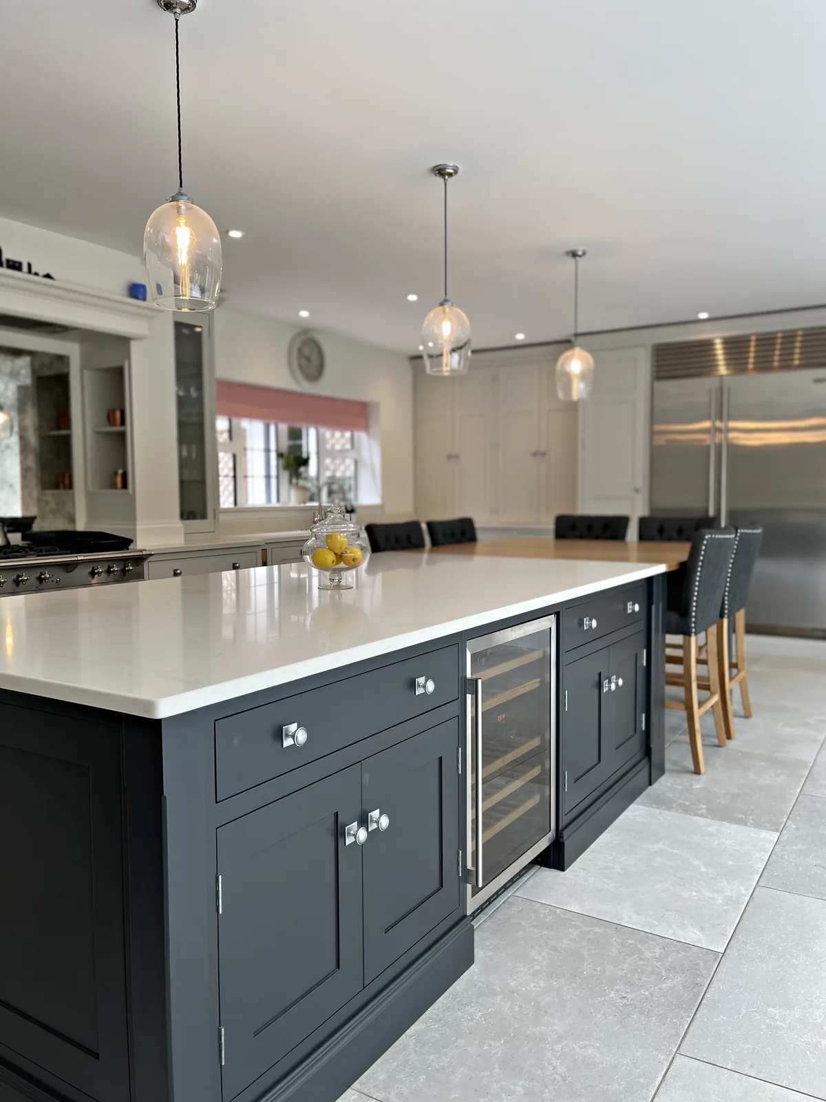 Charcoal island with nickel knobs and a wine cooler under glass pendants