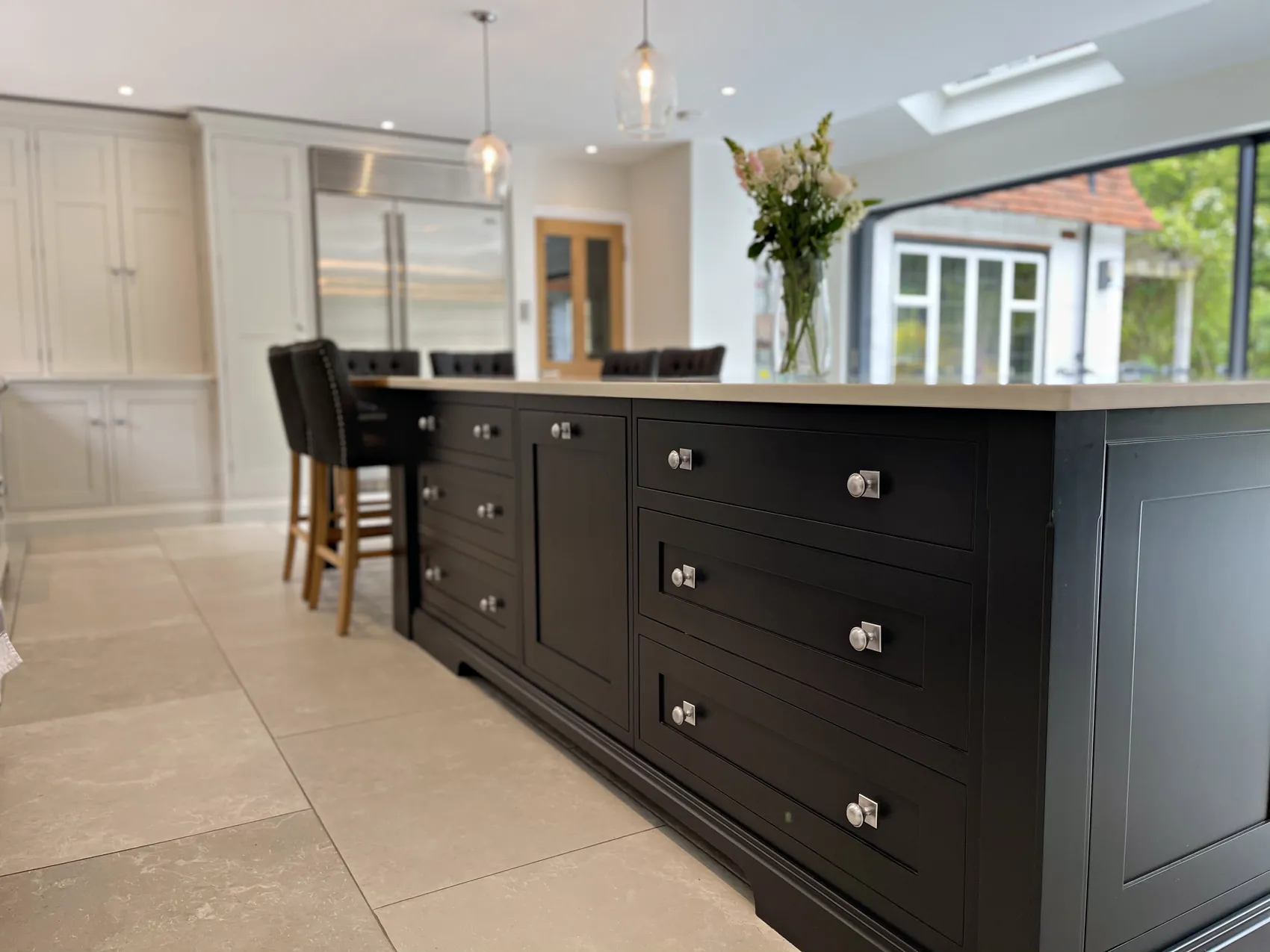 Drawer bank of the Off Black island with nickel knobs, bar stools and the garden doors beyond