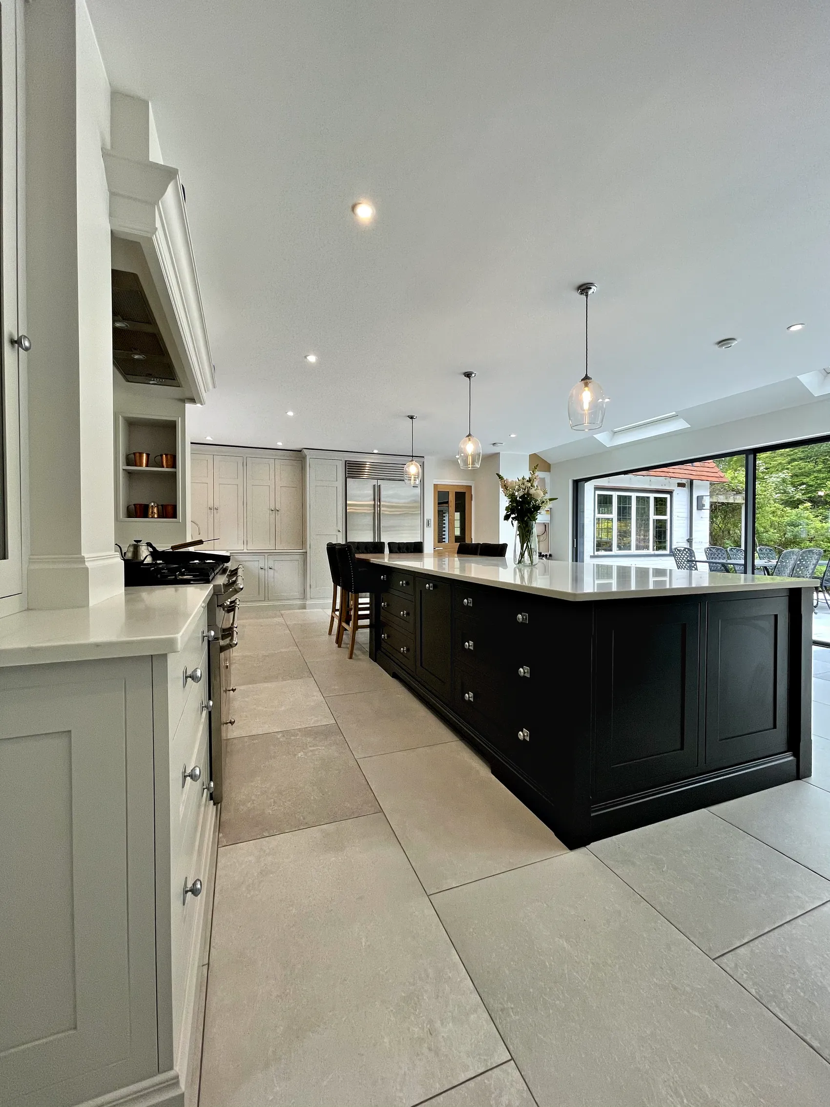Long charcoal island with a white quartz top leading to wide glazed garden doors