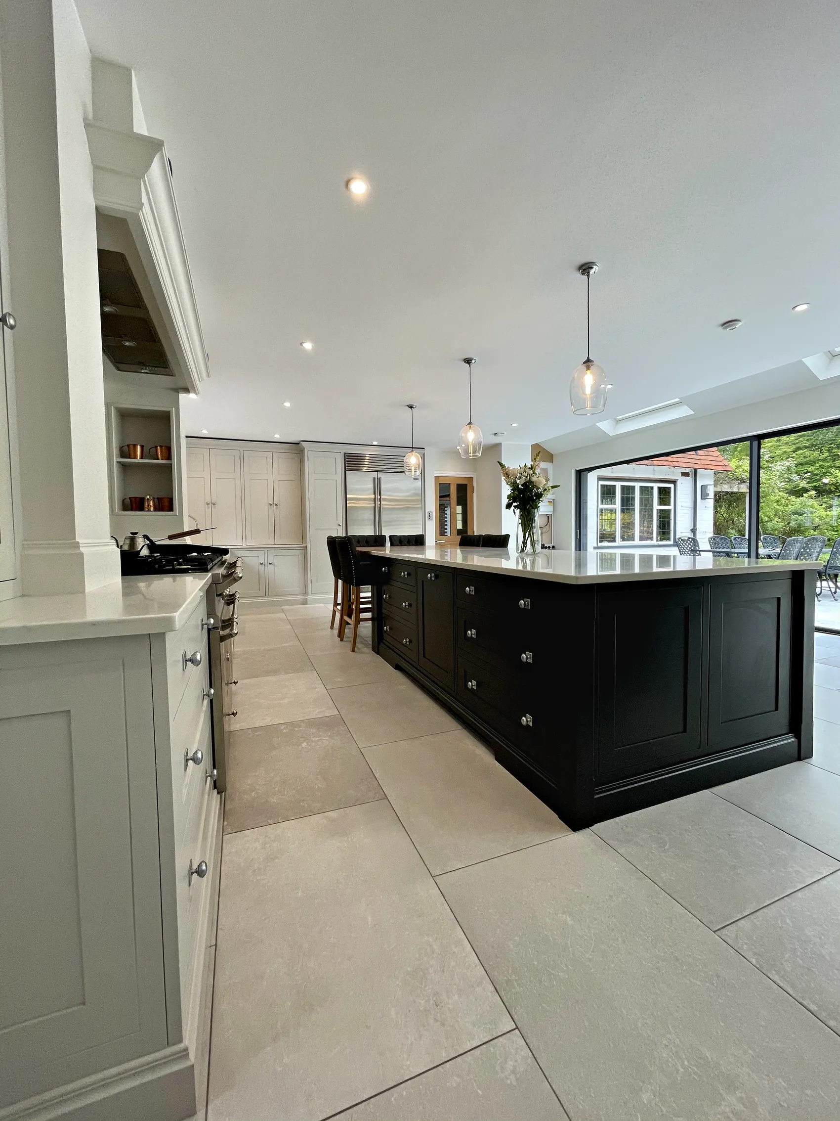 Long charcoal island and a pale grey range wall leading to a bright garden room