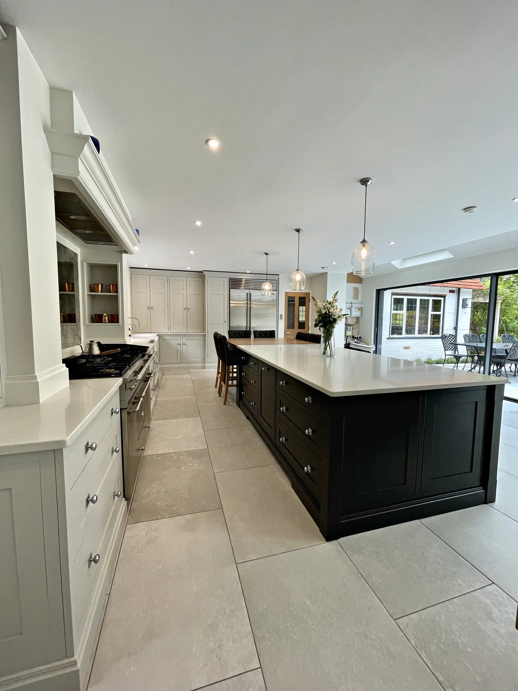 Charcoal island beside a pale grey glazed dresser, looking down the room to the garden doors