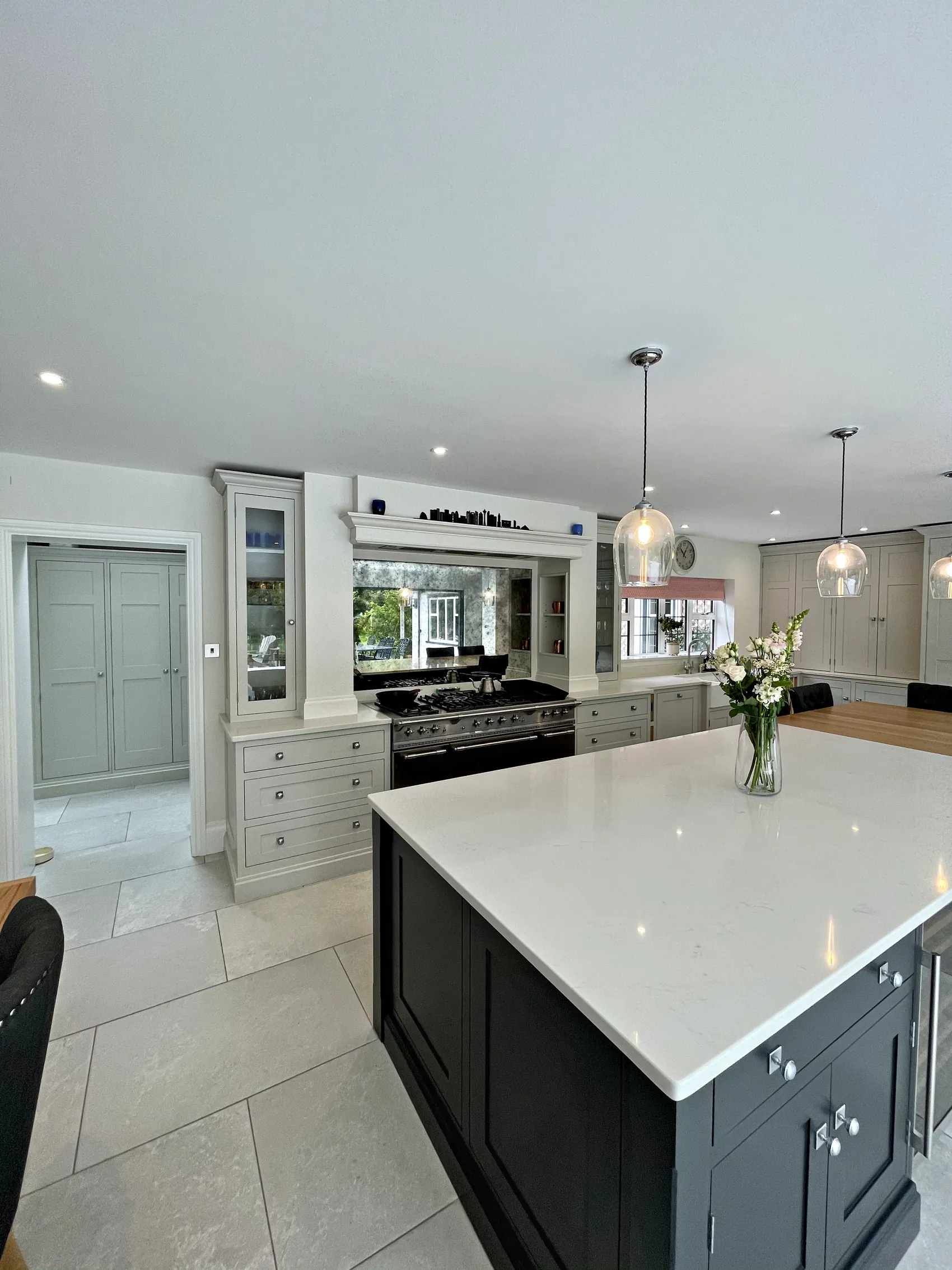 Charcoal island in front of a range wall with an antiqued mirror splashback and a glazed dresser