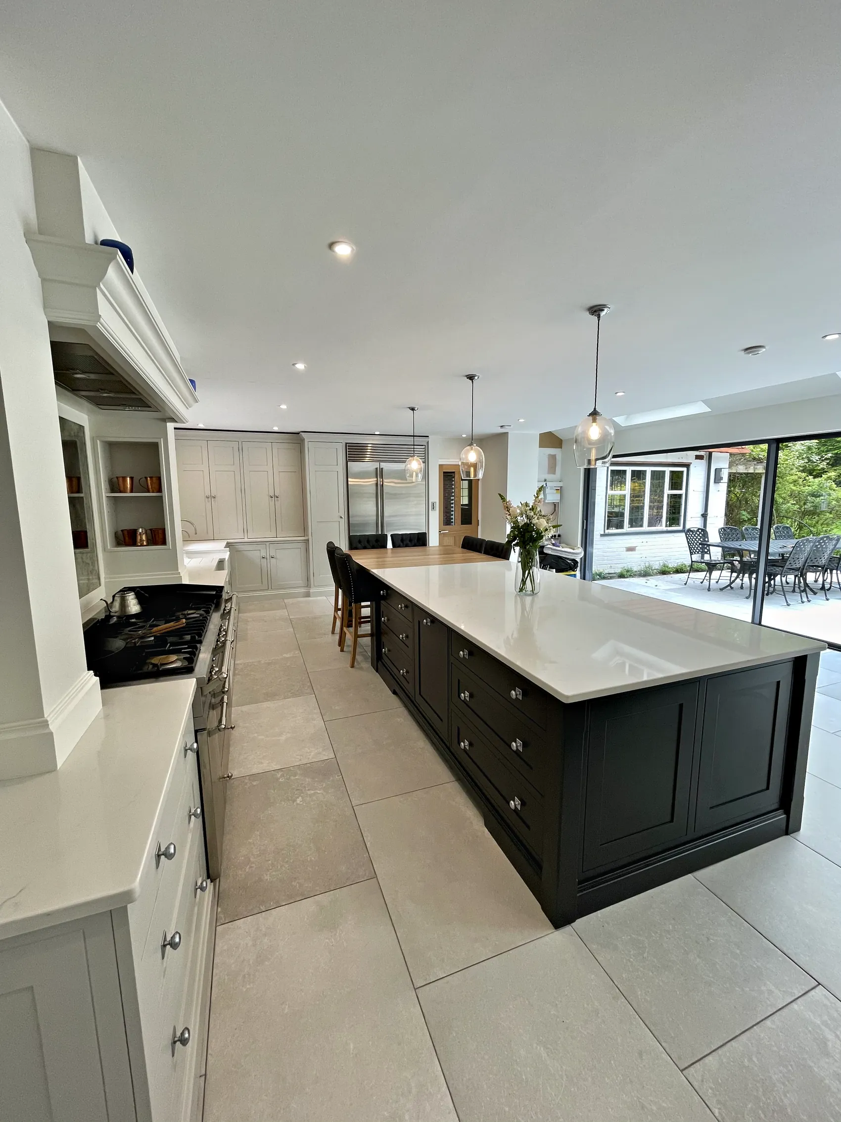 Long charcoal island with a white quartz top running towards wide glazed garden doors