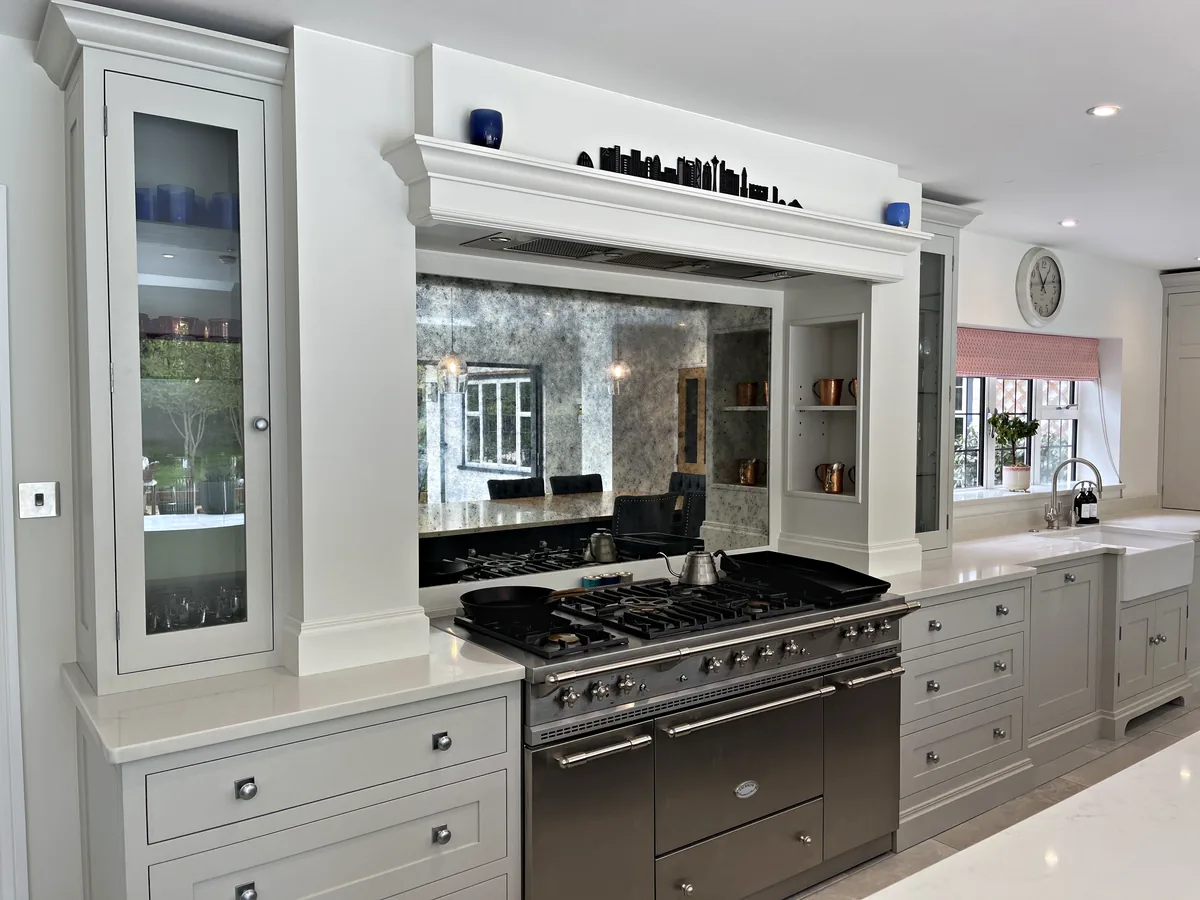 Range cooker under a painted mantel with an antiqued mirror splashback beside a glazed dresser