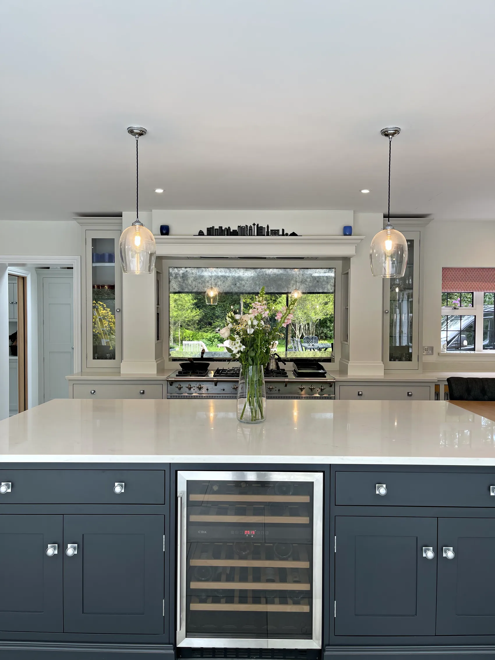 Charcoal island front under two glass pendants with a mirrored range wall beyond