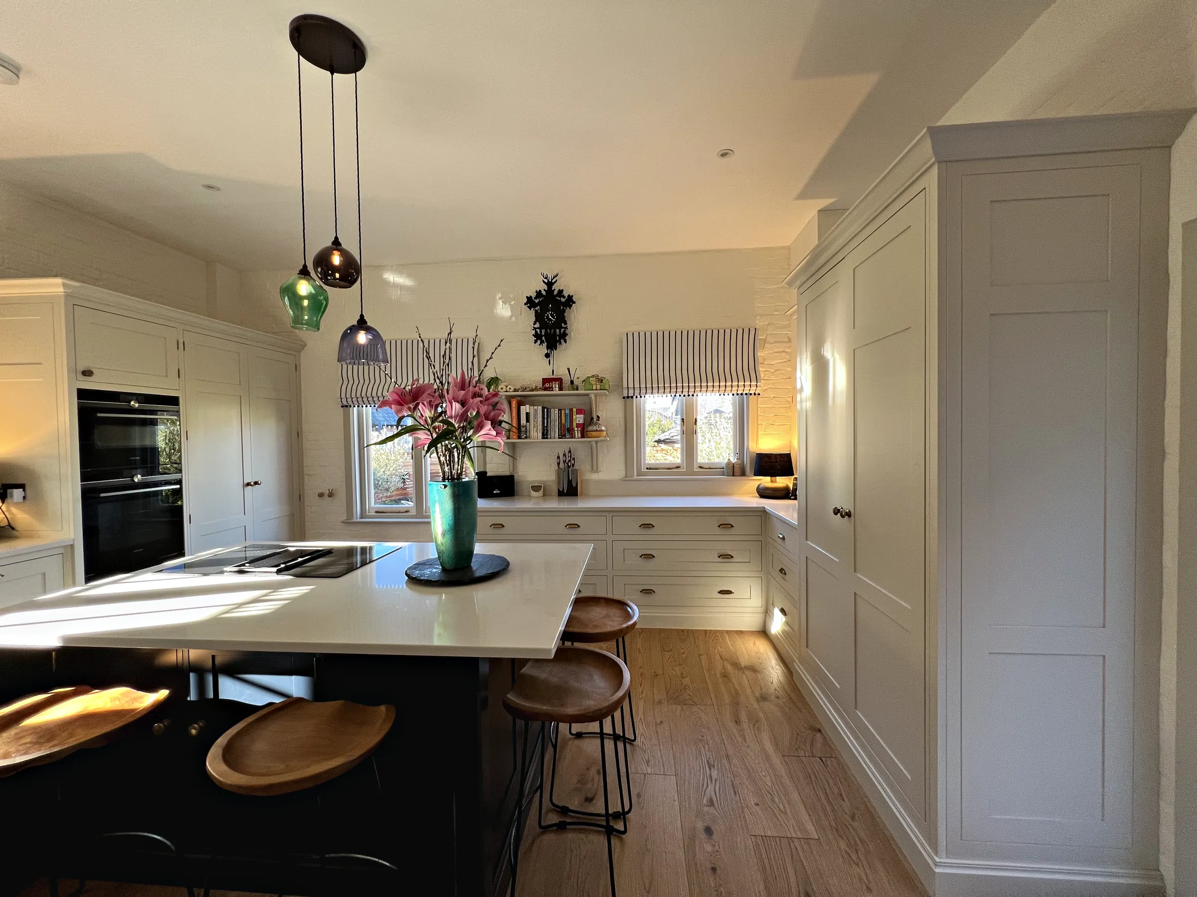 Plimsoll island with leather topped stools in front of the ovens and a tall cupboard