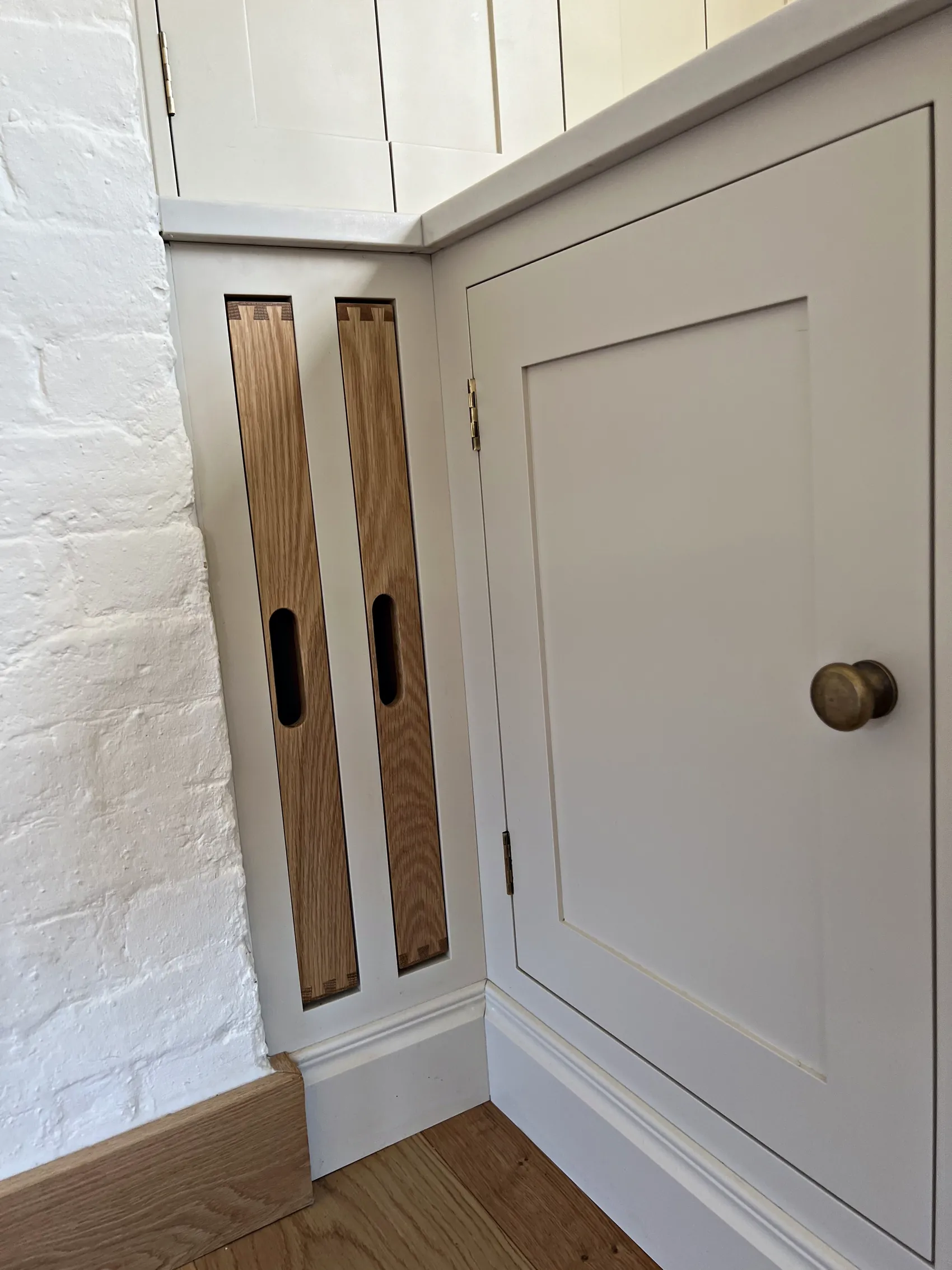 Oak tray slots beside a cream cupboard with an antique brass knob