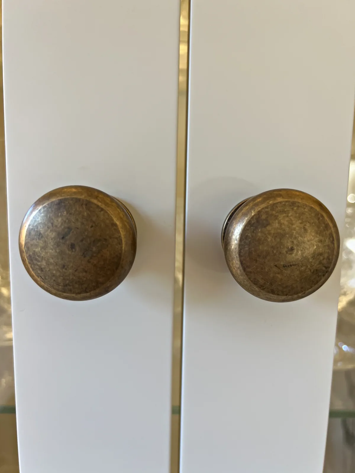 Pair of antique bronze knobs on cream painted cupboard doors