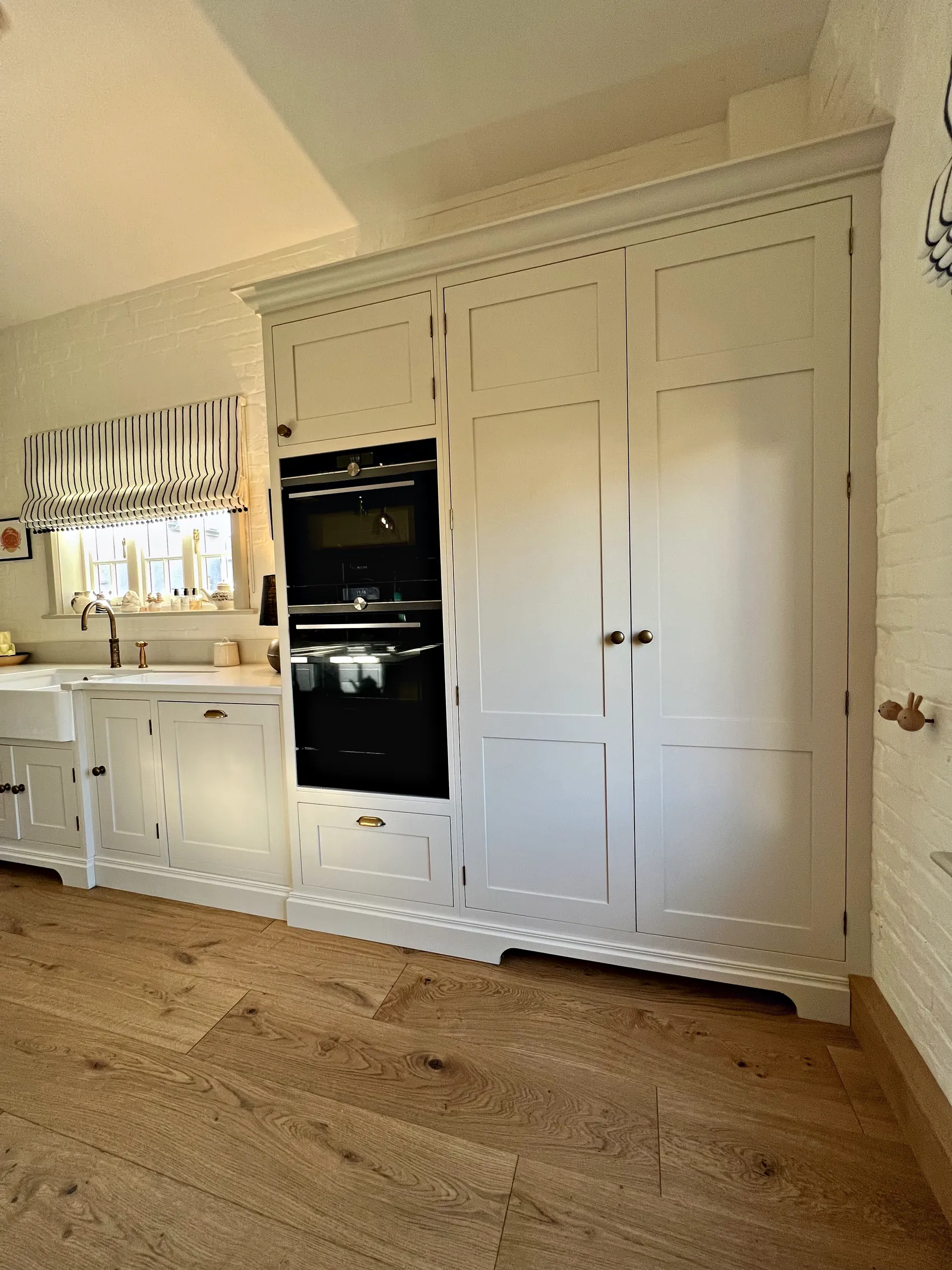 Tall cream cupboards with built in ovens beside the sink run
