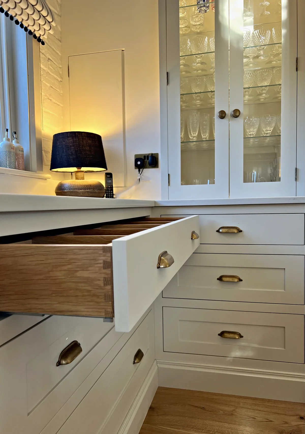 Oak drawer box with dovetail joints pulled out from a cream drawer run