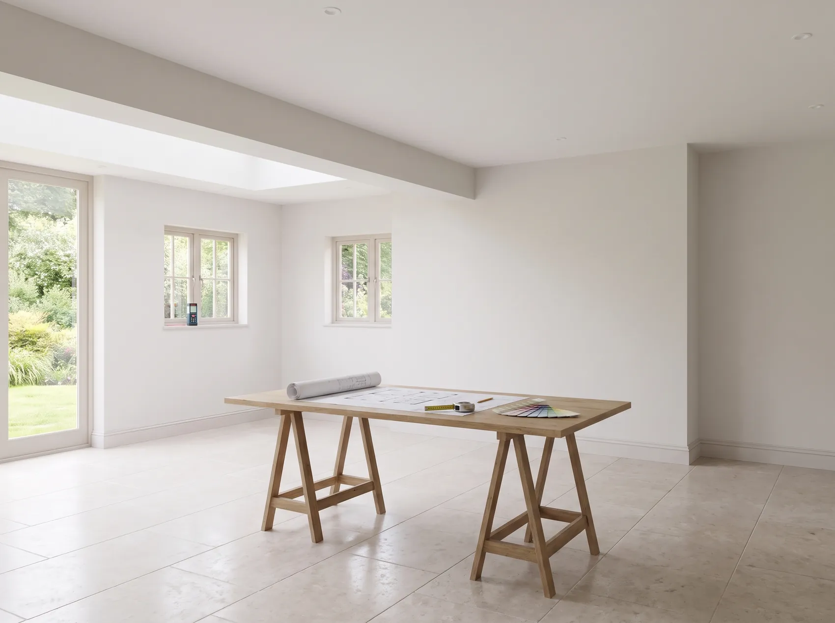 Visualisation of an empty kitchen space with a plan, a tape measure and paint cards laid out for the first measure