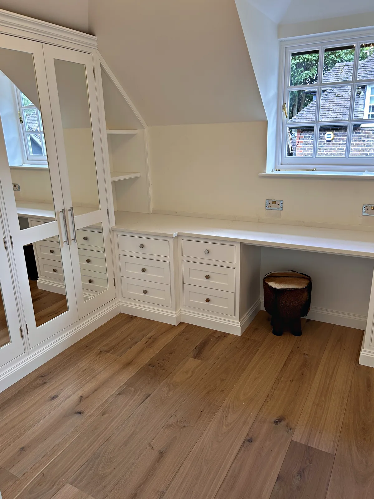 Roughwoods bedroom with mirrored wardrobes and a dressing desk with drawers below a dormer window