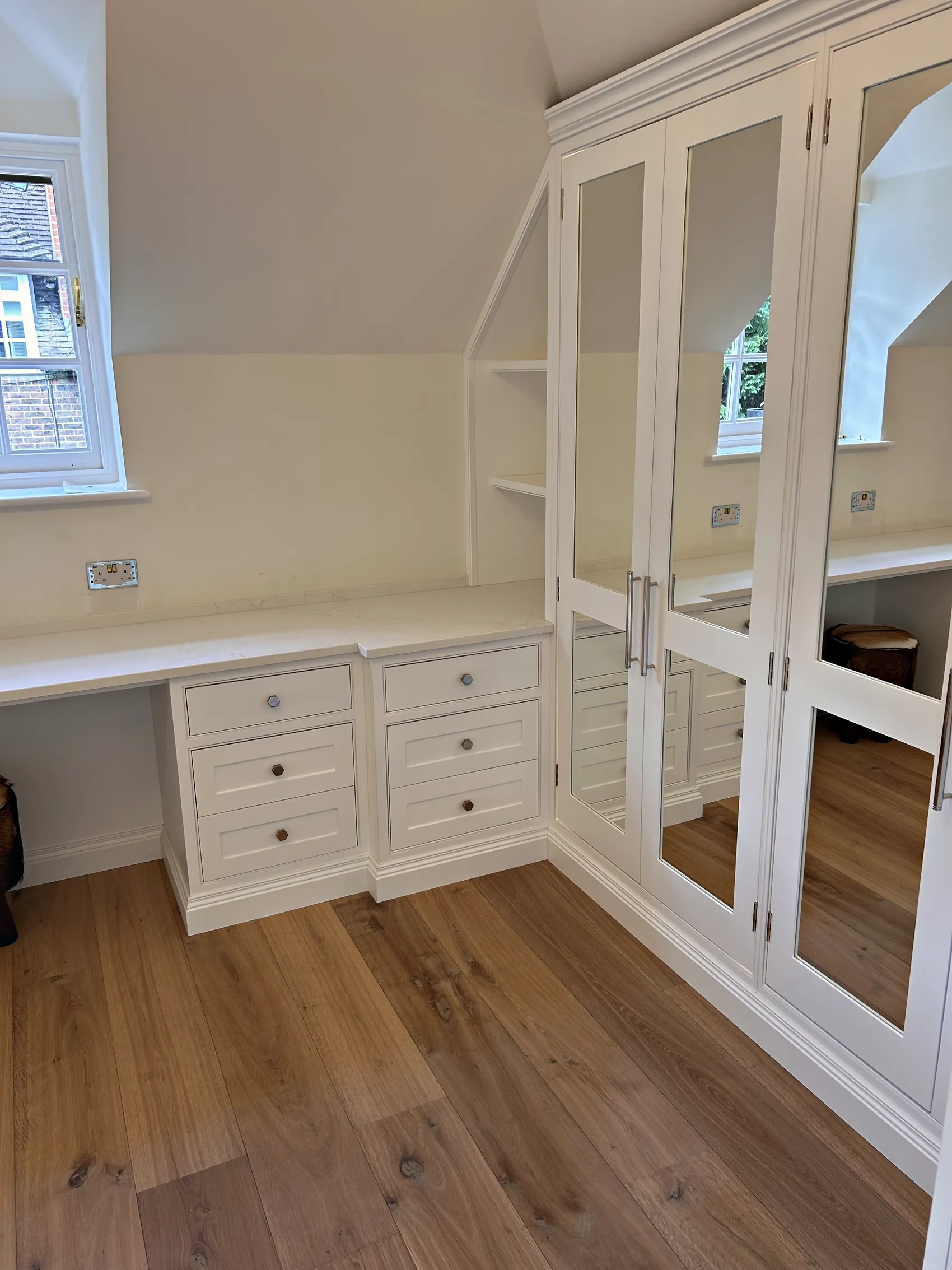 Mirrored wardrobe doors, open shelves and drawer pedestals under the eaves