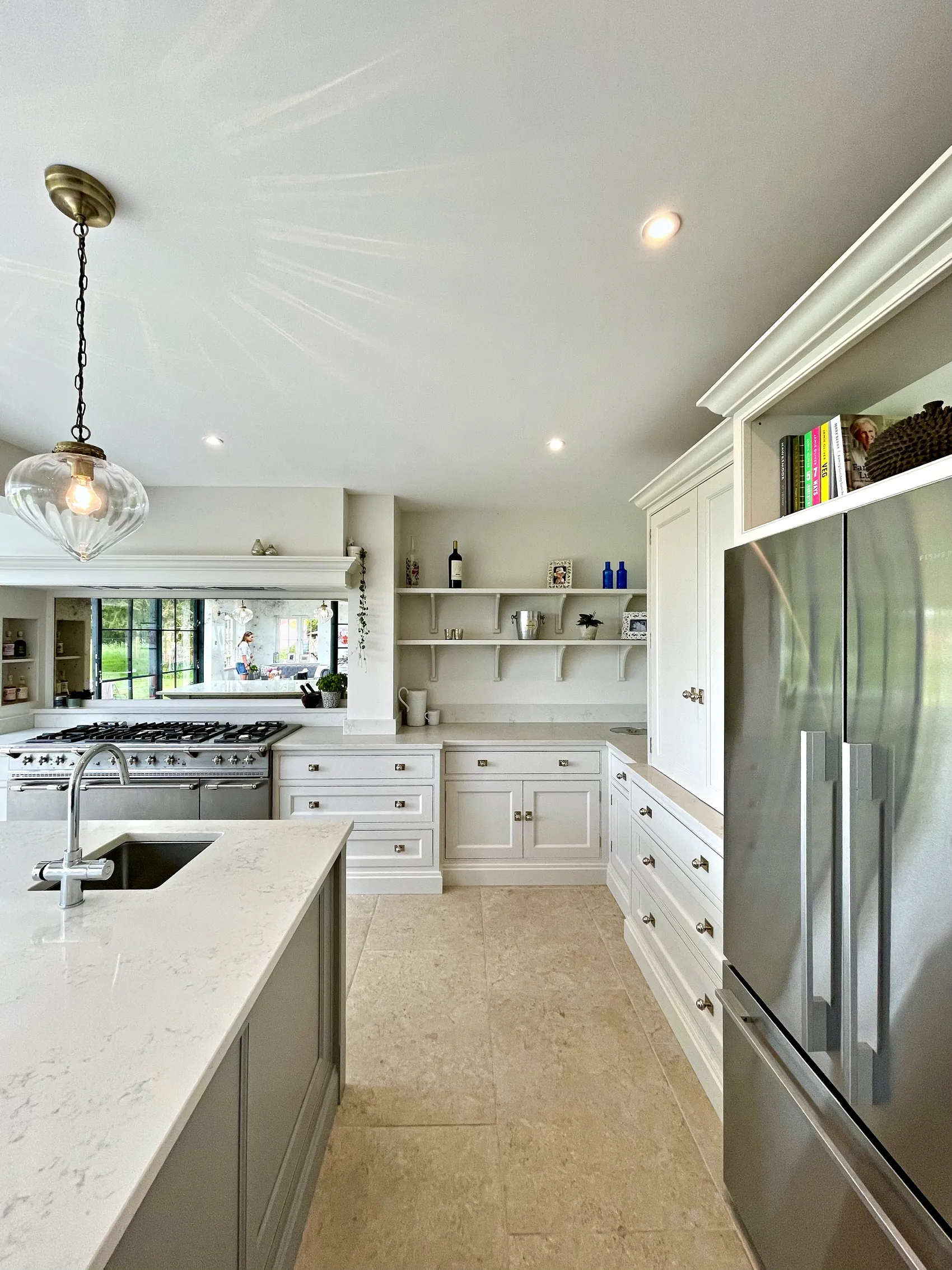 Wrens Hill island sink with a brushed tap, the range wall and tall fridge housing under glass pendants