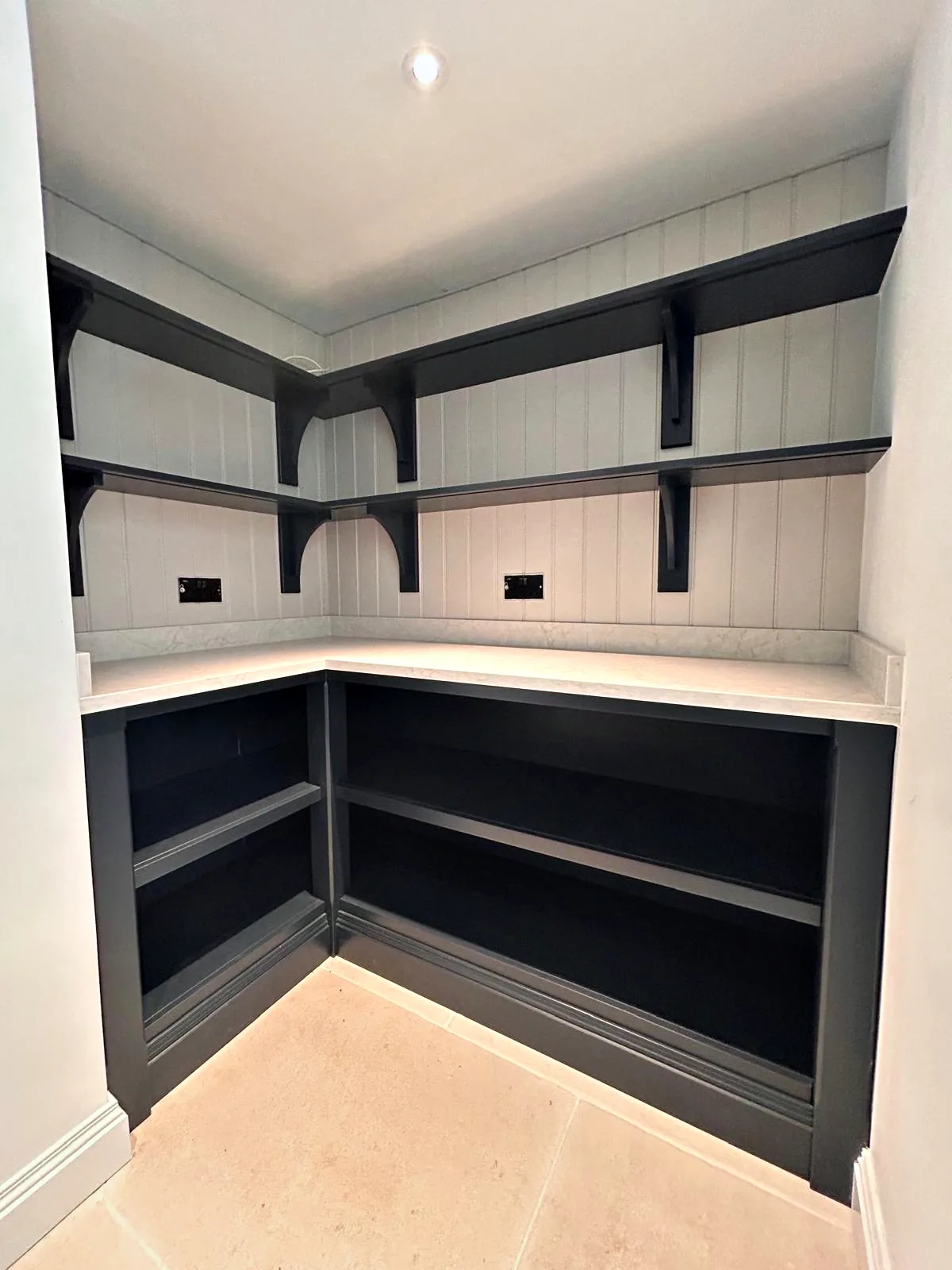 Walk in pantry corner with charcoal open shelving, a quartz top and shelves on dark brackets