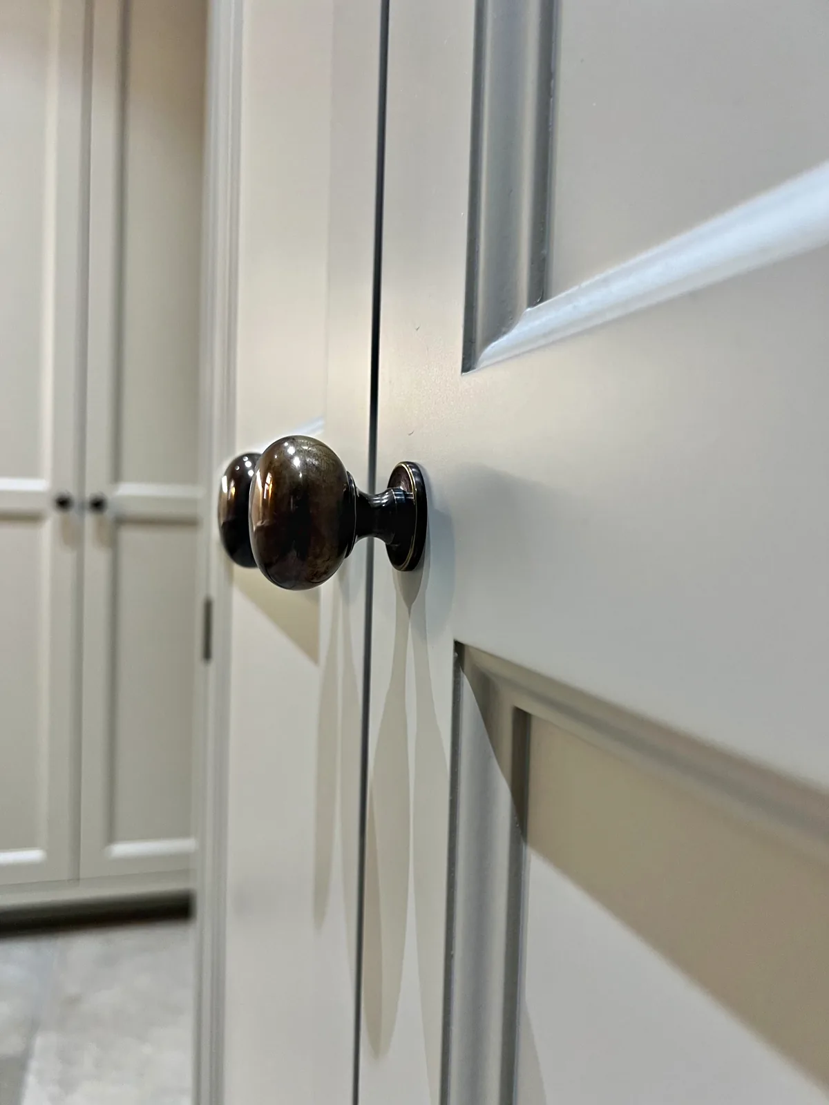 Antique bronze knob on a pale grey painted cupboard door